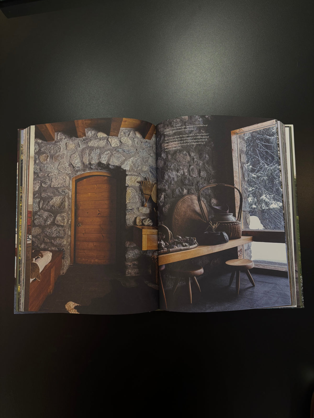 An open book or magazine spread showing a rustic interior scene with stone walls wooden door table window
