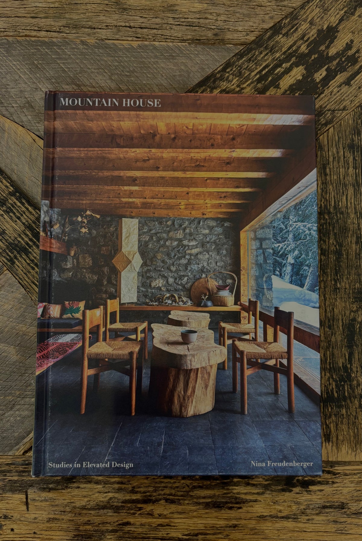 A hardcover book titled 'Mountain House: Studies in Elevated Design' by Nina Wyndenschuster, featuring a rustic interior dining room cover
