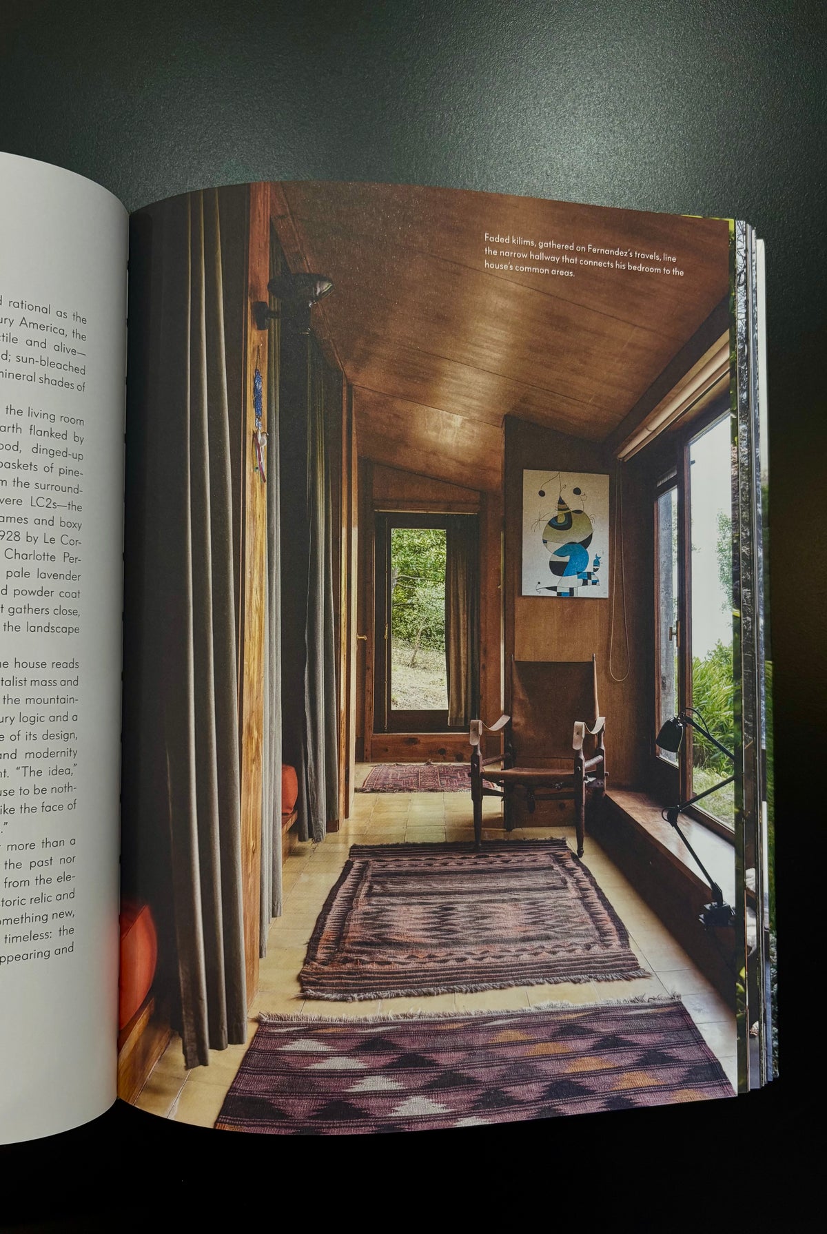 photograph of a rustic room with wood walls, windows, rugs, and a chair rustic home