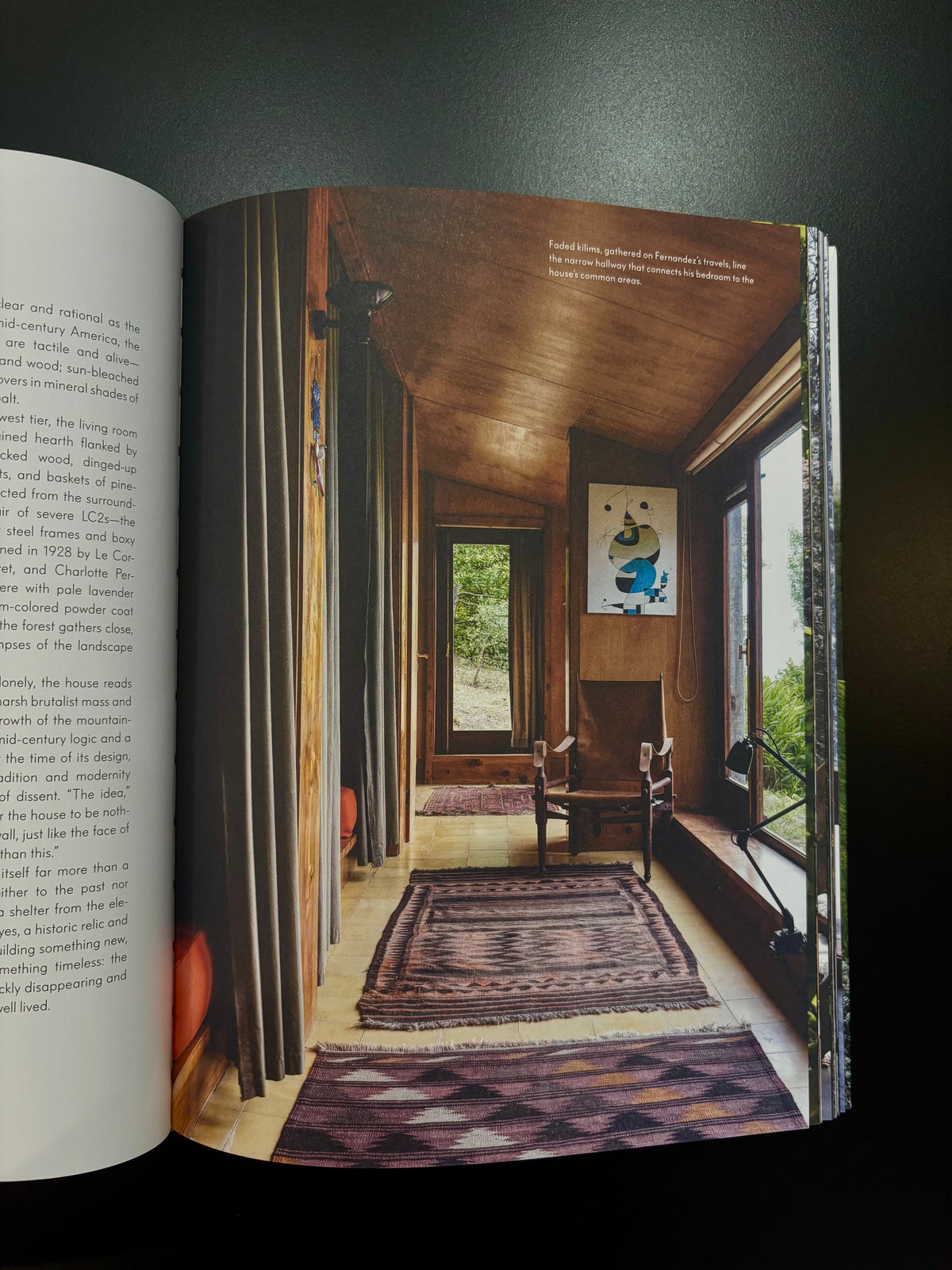 photograph of a rustic room with wood walls, windows, rugs, and a chair rustic home