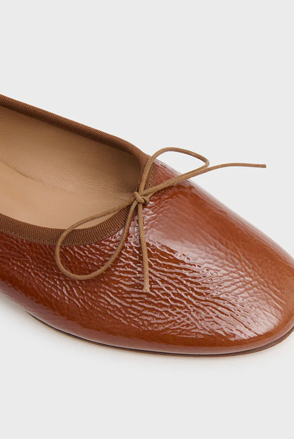 Brown leather flat ballet flat with a bow on a white background by luxury footwear designer Mansur Gavriel