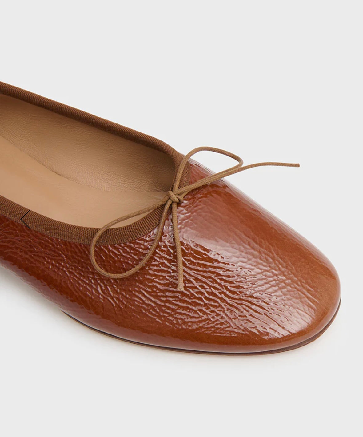 Brown leather flat ballet flat with a bow on a white background by luxury footwear designer Mansur Gavriel