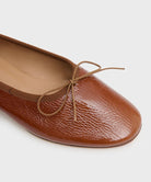 Brown leather flat ballet flat with a bow on a white background by luxury footwear designer Mansur Gavriel