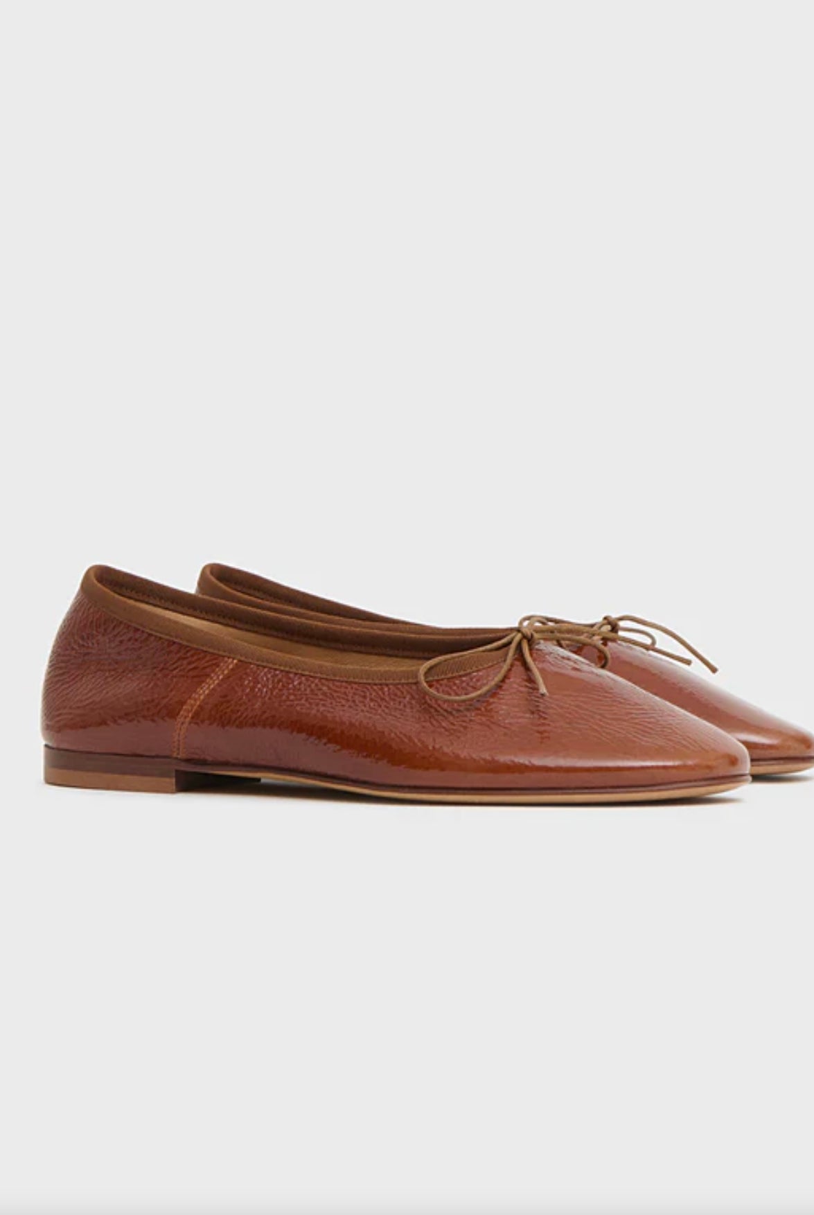 Brown leather flat ballet flats with a bow on a white background by luxury footwear designer Mansur Gavriel