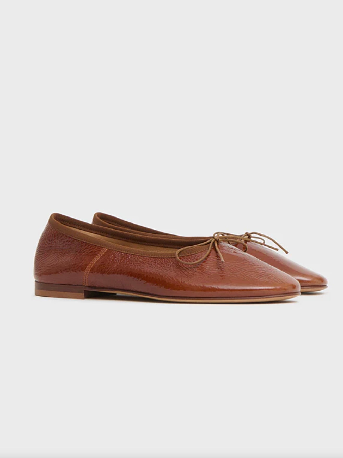 Brown leather flat ballet flats with a bow on a white background by luxury footwear designer Mansur Gavriel