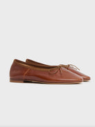 Brown leather flat ballet flats with a bow on a white background by luxury footwear designer Mansur Gavriel