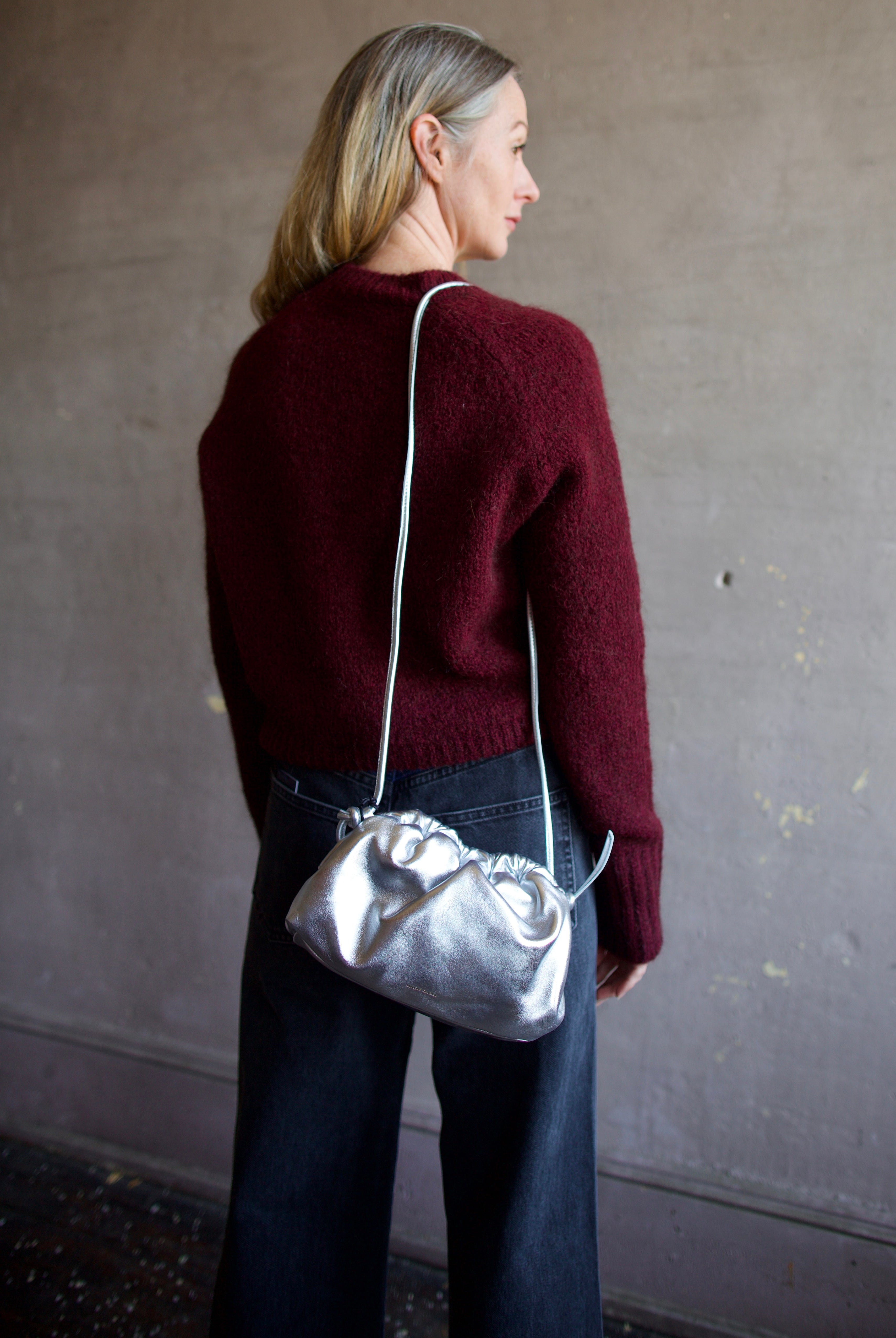 Model wearing the Italian leather Mini Cloud clutch by high-end designer Mansur Gavriel in metallic silver