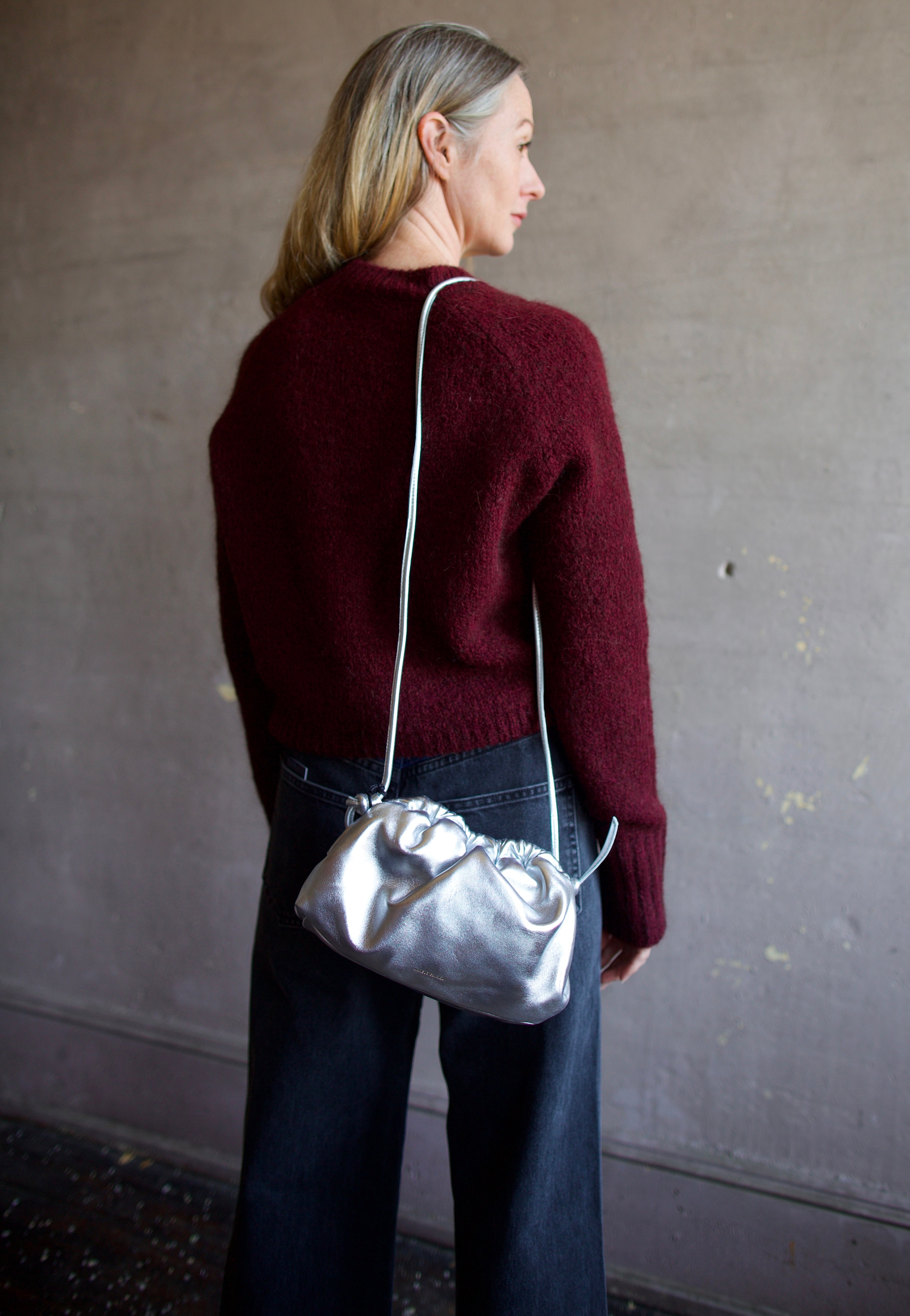 Model wearing the Italian leather Mini Cloud clutch by high-end designer Mansur Gavriel in metallic silver
