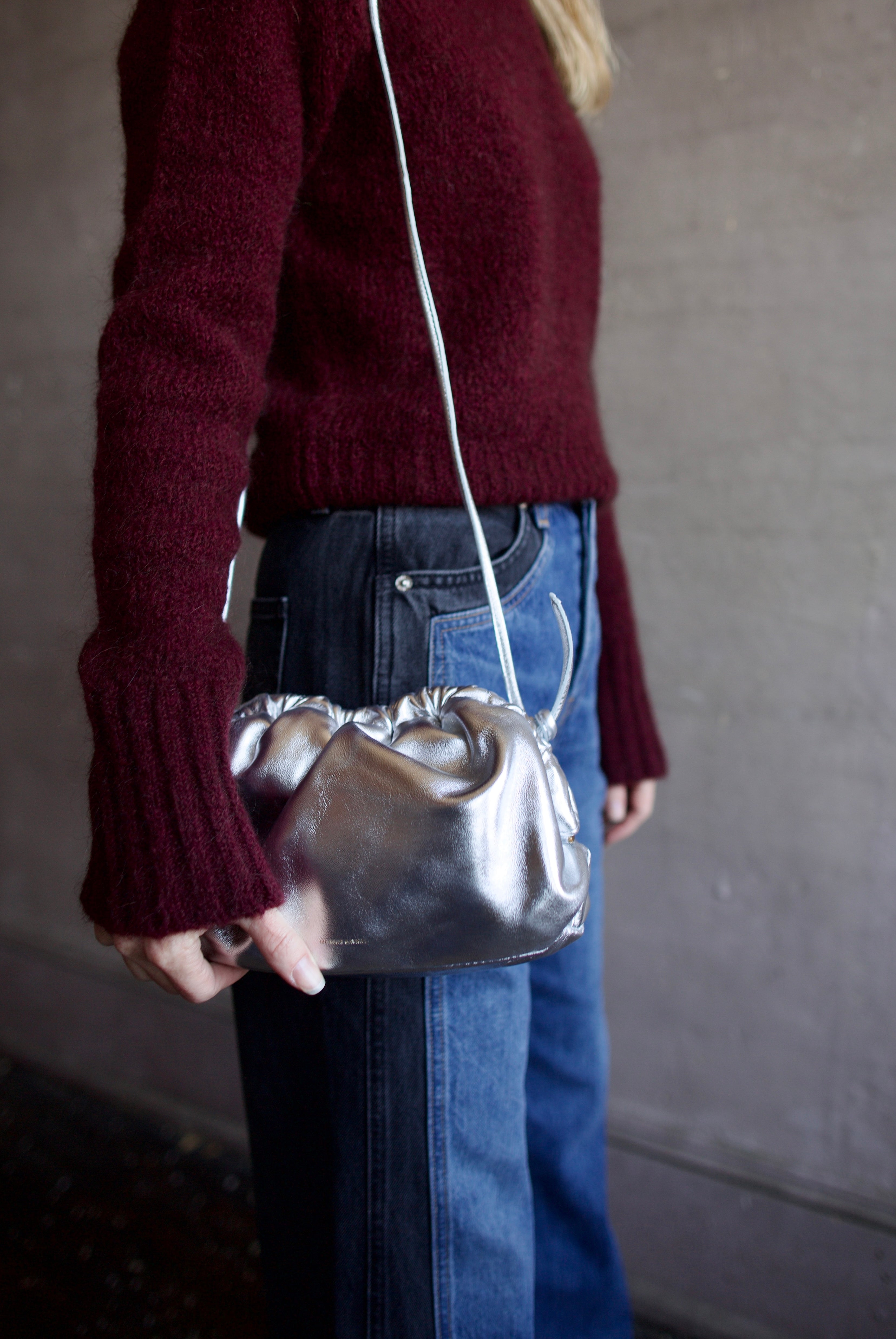 Model wearing the Italian leather Mini Cloud clutch by high-end designer Mansur Gavriel in metallic silver