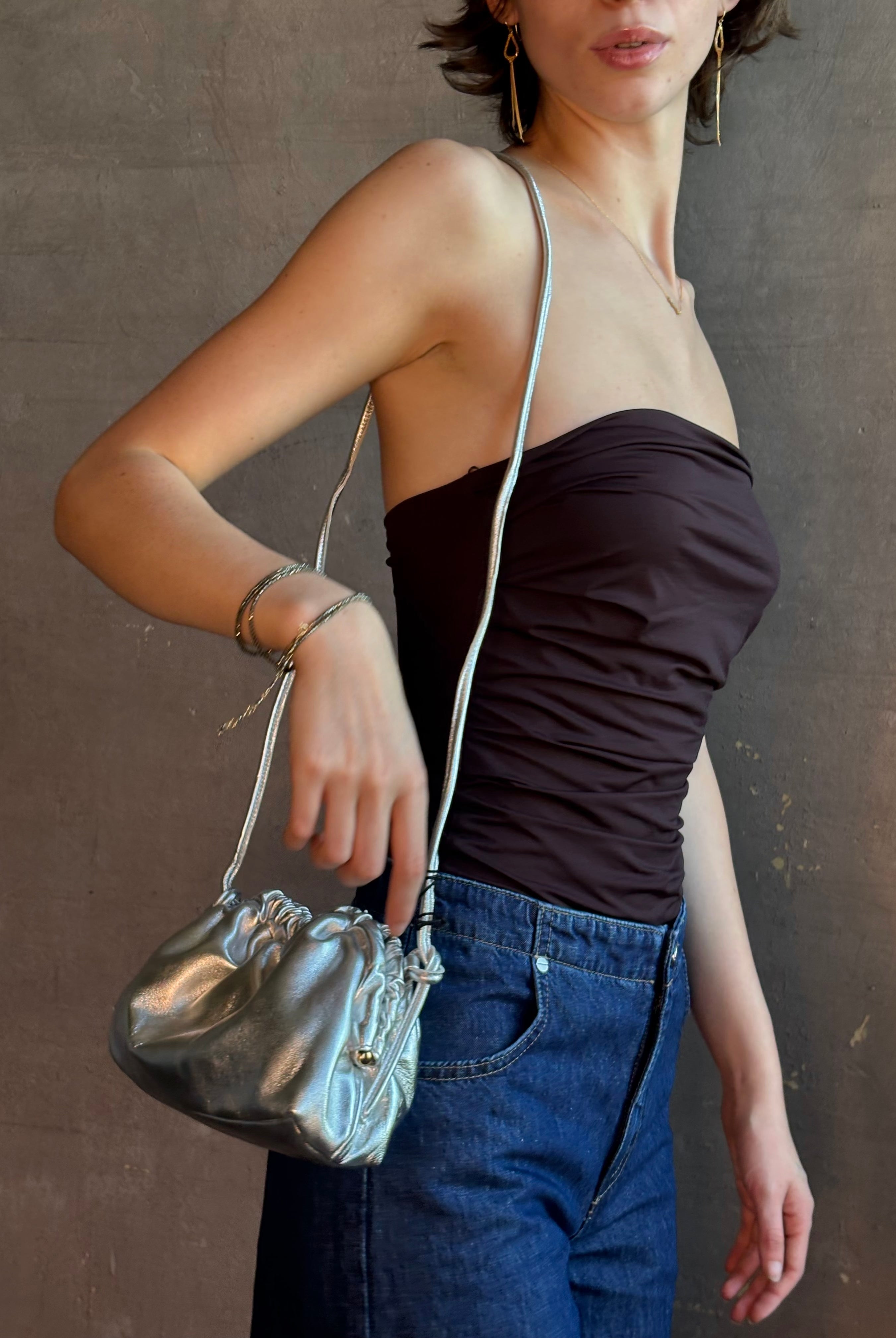 Woman wearing the Italian leather Mini Cloud crossbody by high-end designer Mansur Gavriel in metallic silver with removeable shoulder strap that can also double as a clutch