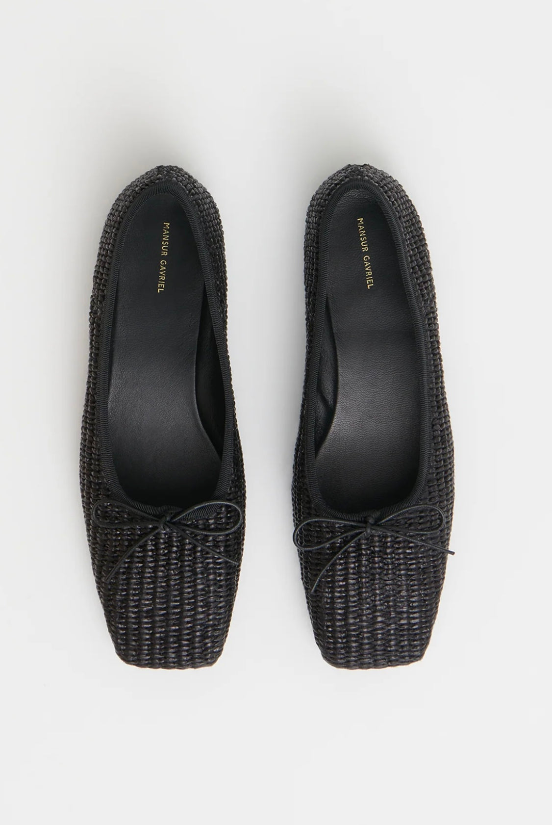 Pair of black woven raffia ballet flats with a square toe and bowtie by high-end footwear designer Mansur Gavriel