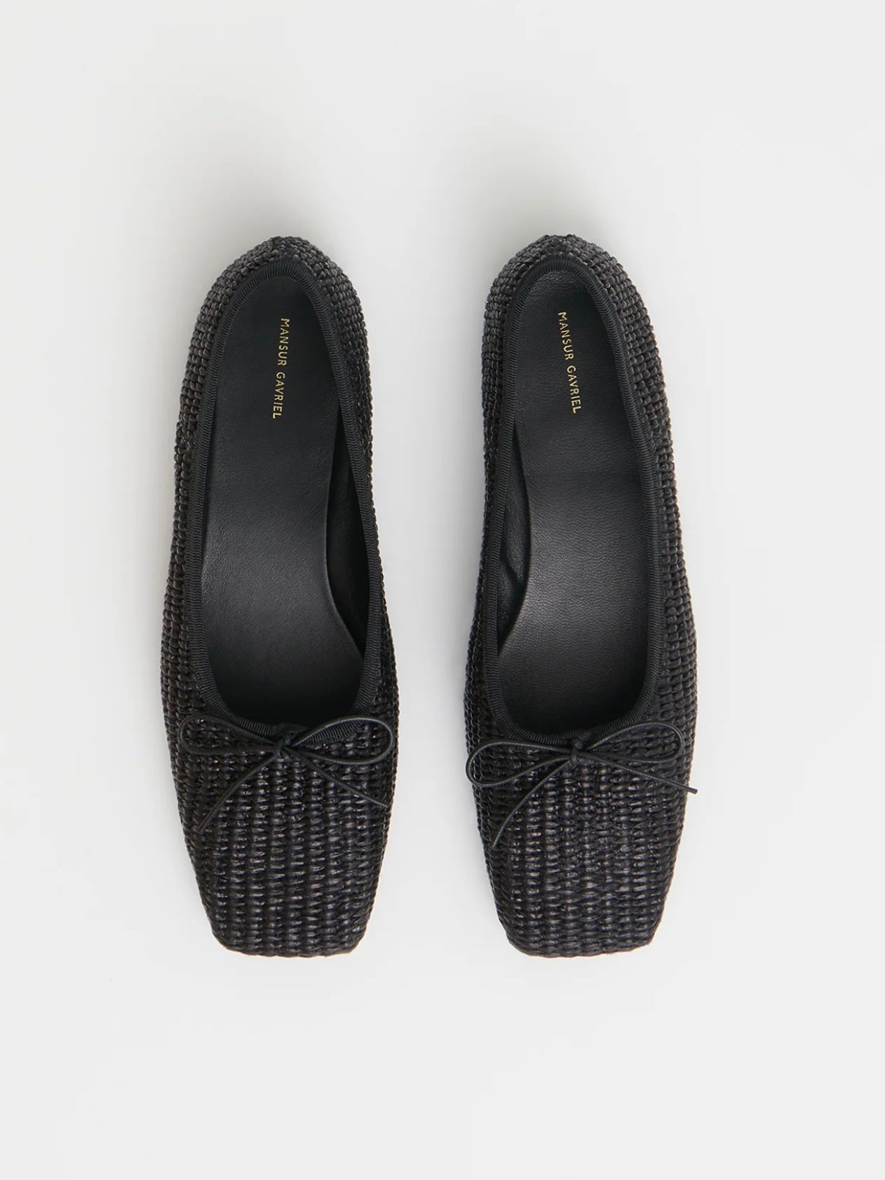 Pair of black woven raffia ballet flats with a square toe and bowtie by high-end footwear designer Mansur Gavriel
