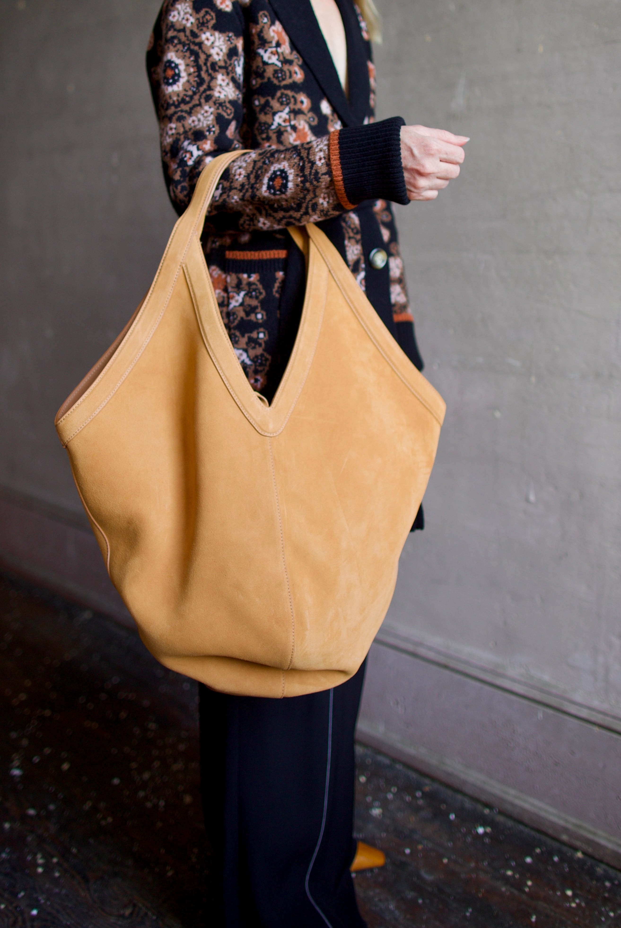 Model holding the Luxury Italian leather large hobo by designer Mansur Gavriel  with v-detail handle in camel color