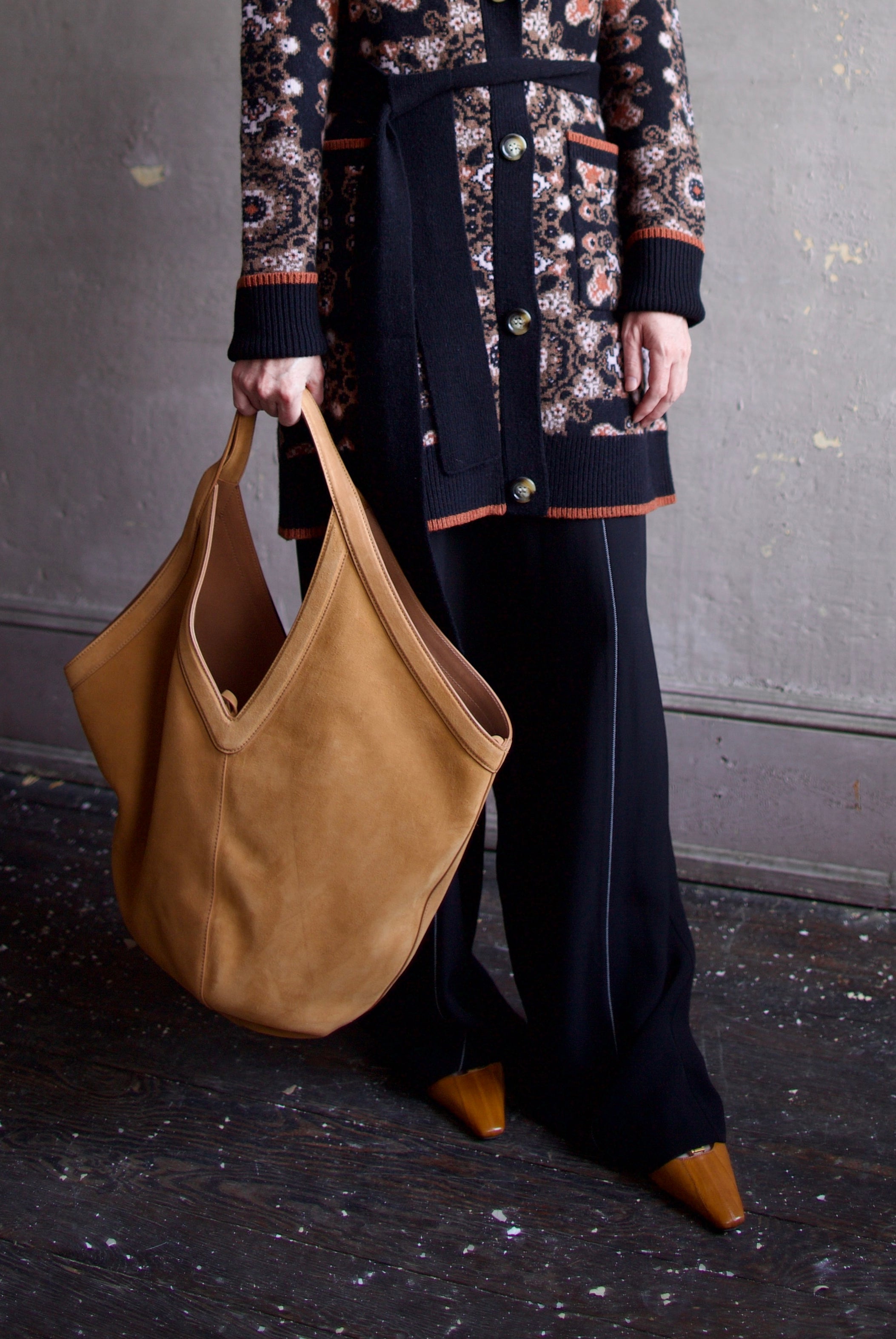 Model holding the Mansur Gavriel soft hobo with a double tie closure, oversized and a shoulder handle with v-detail in light brown suede leather.