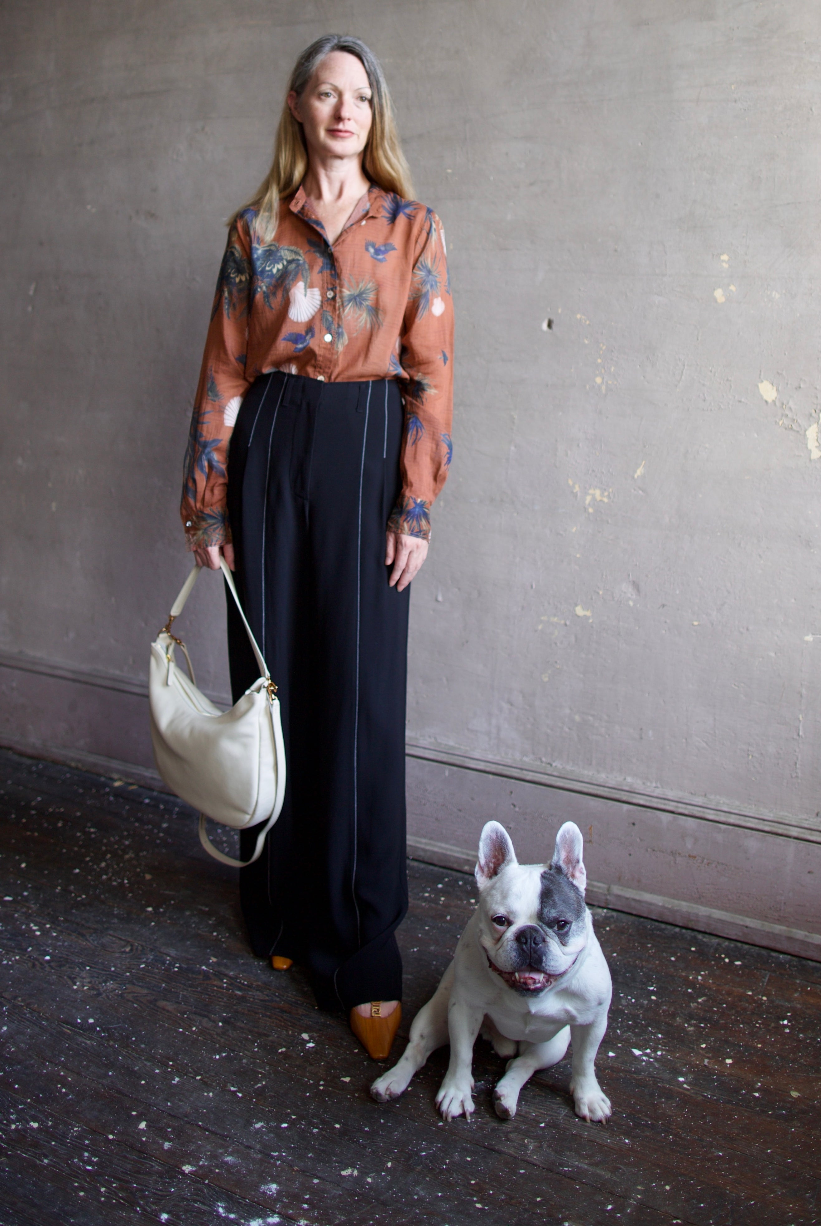French bulldog and mature model wearing the Swing Bag by High-end designer Mansur Gavriel in cream color with gold finish hardware