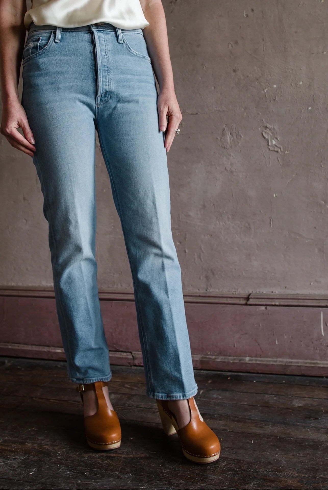 woman wearing Mother denim that is high-rise ankle length straight leg jean with finished hem light wash Made in USA