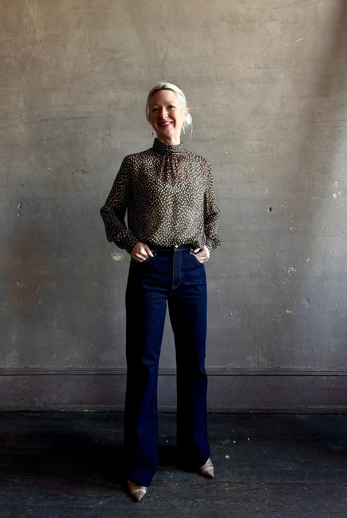 Mature woman wearing Nili Lotan Silk Demie Blouse in Brown/Cream Wild Dots sheer mock neck and keyhole back closure. Made in the USA