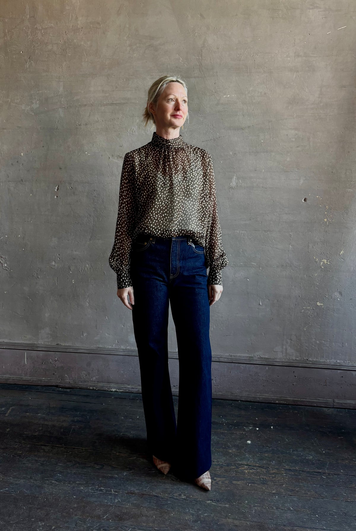 Mature woman wearing Nili Lotan Silk Demie Blouse in Brown/Cream Wild Dots sheer mock neck and keyhole back closure. Made in the USA