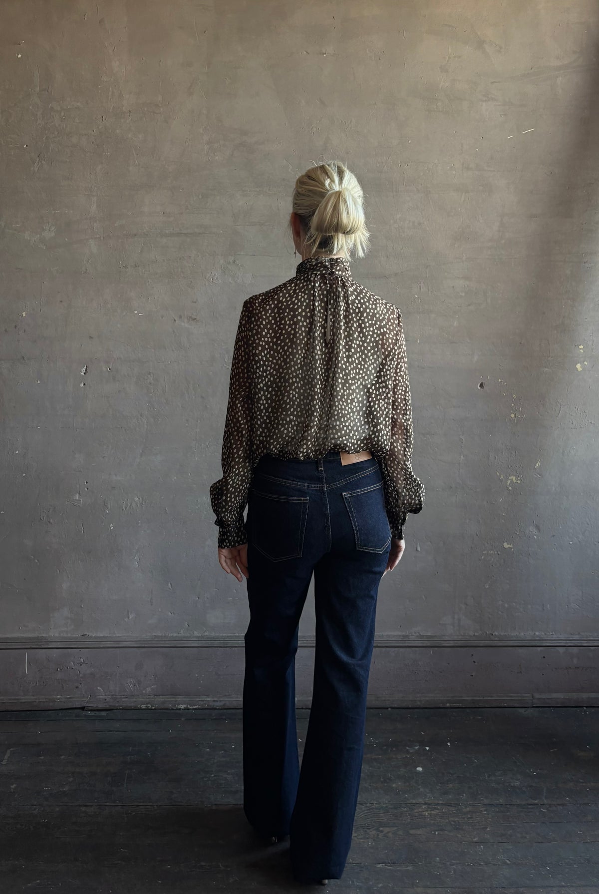 Mature woman wearing Nili Lotan Silk Demie Blouse in Brown/Cream Wild Dots sheer mock neck and keyhole back closure. Made in the USA