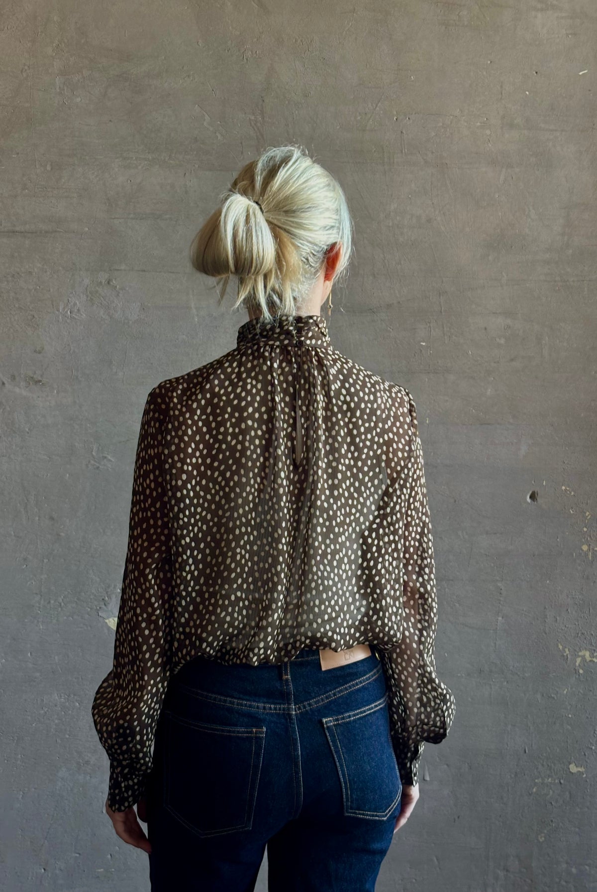 Mature woman wearing Nili Lotan Silk Demie Blouse in Brown/Cream Wild Dots sheer mock neck and keyhole back closure. Made in the USA