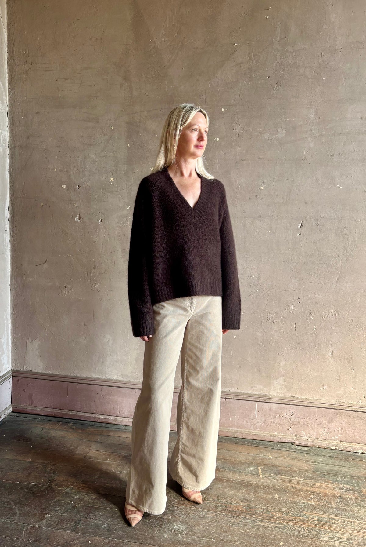 Mature woman wearing Nili Lotan's Isley Sweater Dark brown cashmere-silk relaxed V-neck silhouette. Ultra-luxe