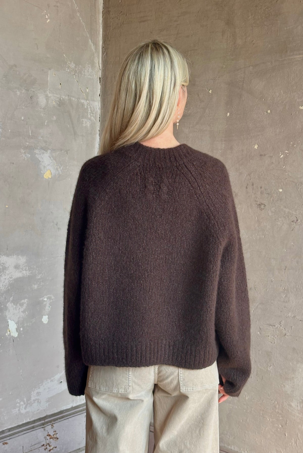 Mature woman wearing Nili Lotan's Isley Sweater Dark brown cashmere-silk relaxed V-neck silhouette. Ultra-luxe
