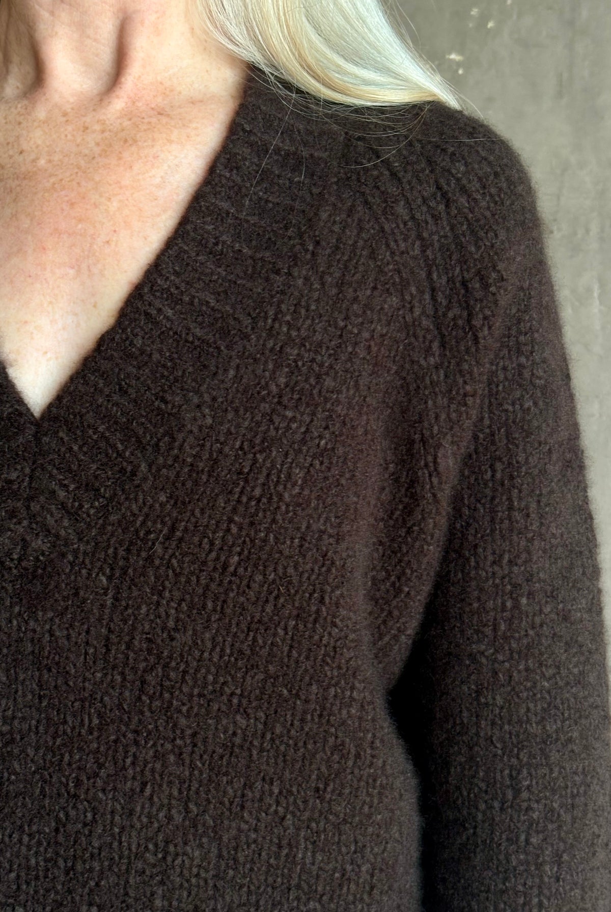 Mature woman wearing Nili Lotan's Isley Sweater Dark brown cashmere-silk relaxed V-neck silhouette. Ultra-luxe