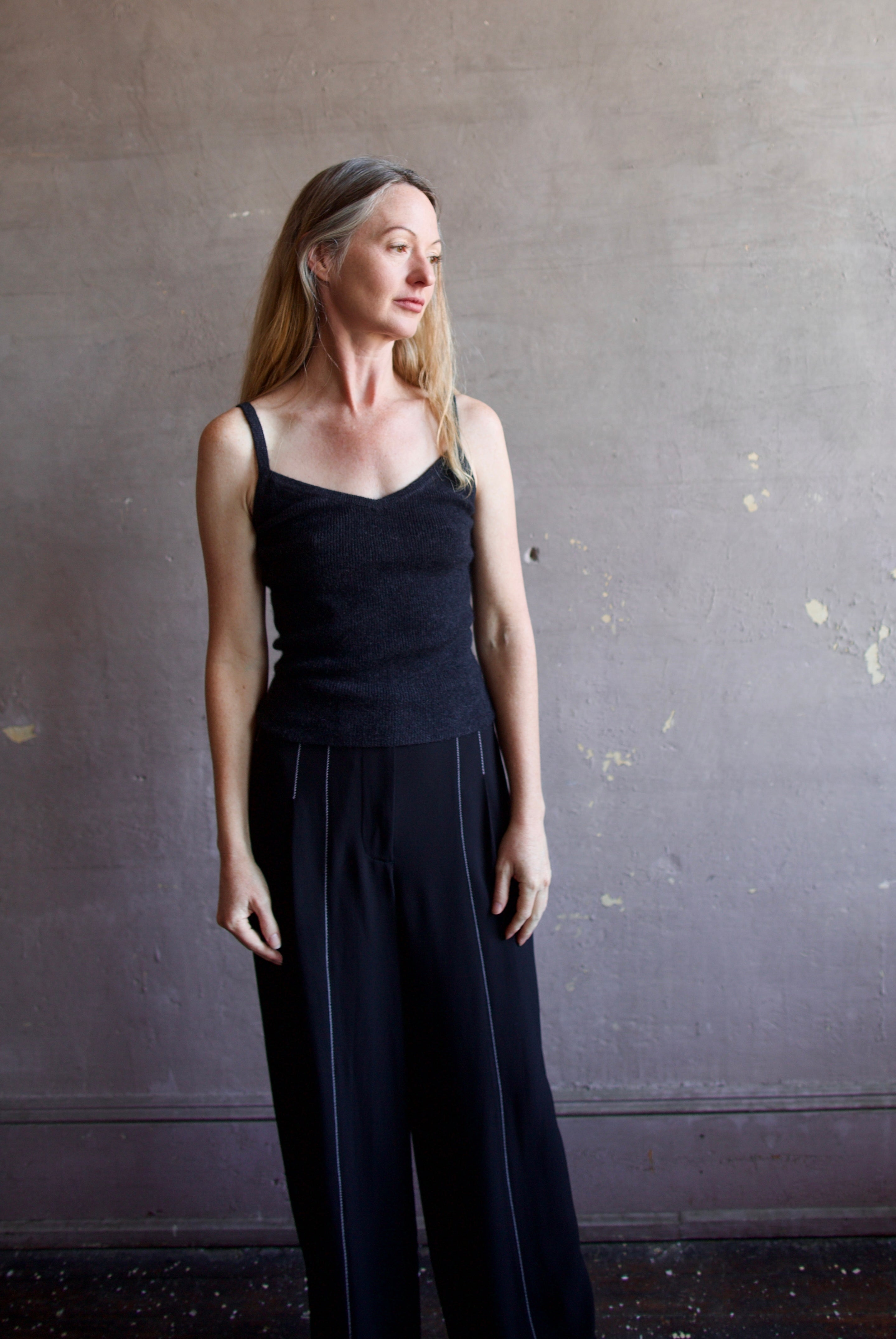 Image featuring a woman wearing the Ribbed Cami by Naadam with a v neckline, thin straps, and tailored fit in charcoal heather grey.