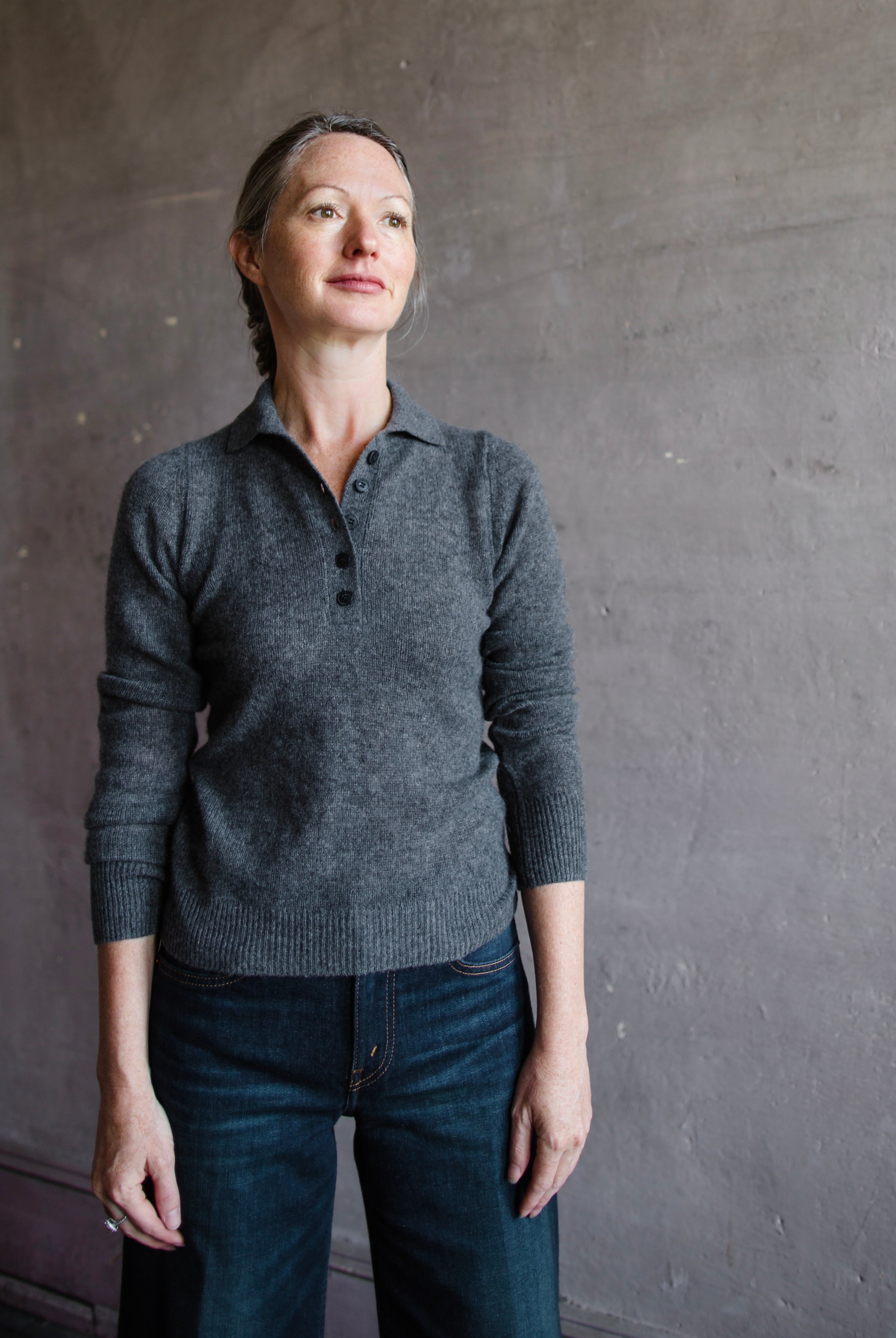 Image featuring a woman wearing the Naadam featherweight cashmere polo in dark grey