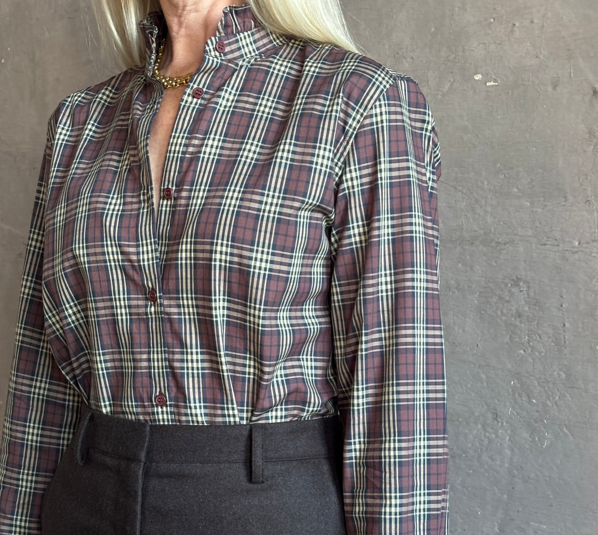 Mature woman wearing a long-sleeve plaid button-up shirt in muted burgundy, beige, and navy paired with a chocolate brown skirt perfect for Fall attire