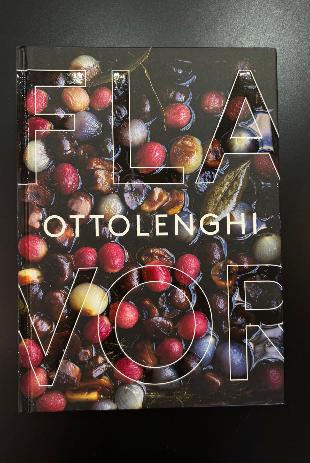 Ottolenghi's 'Flavor' cookbook with a glossy cover featuring a detailed photograph of roasted chestnuts and red fruits