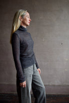 Model wearing a dark ribbed Proenza Schouler striped mock neck sweater and gray Veronica Beard barrel denim