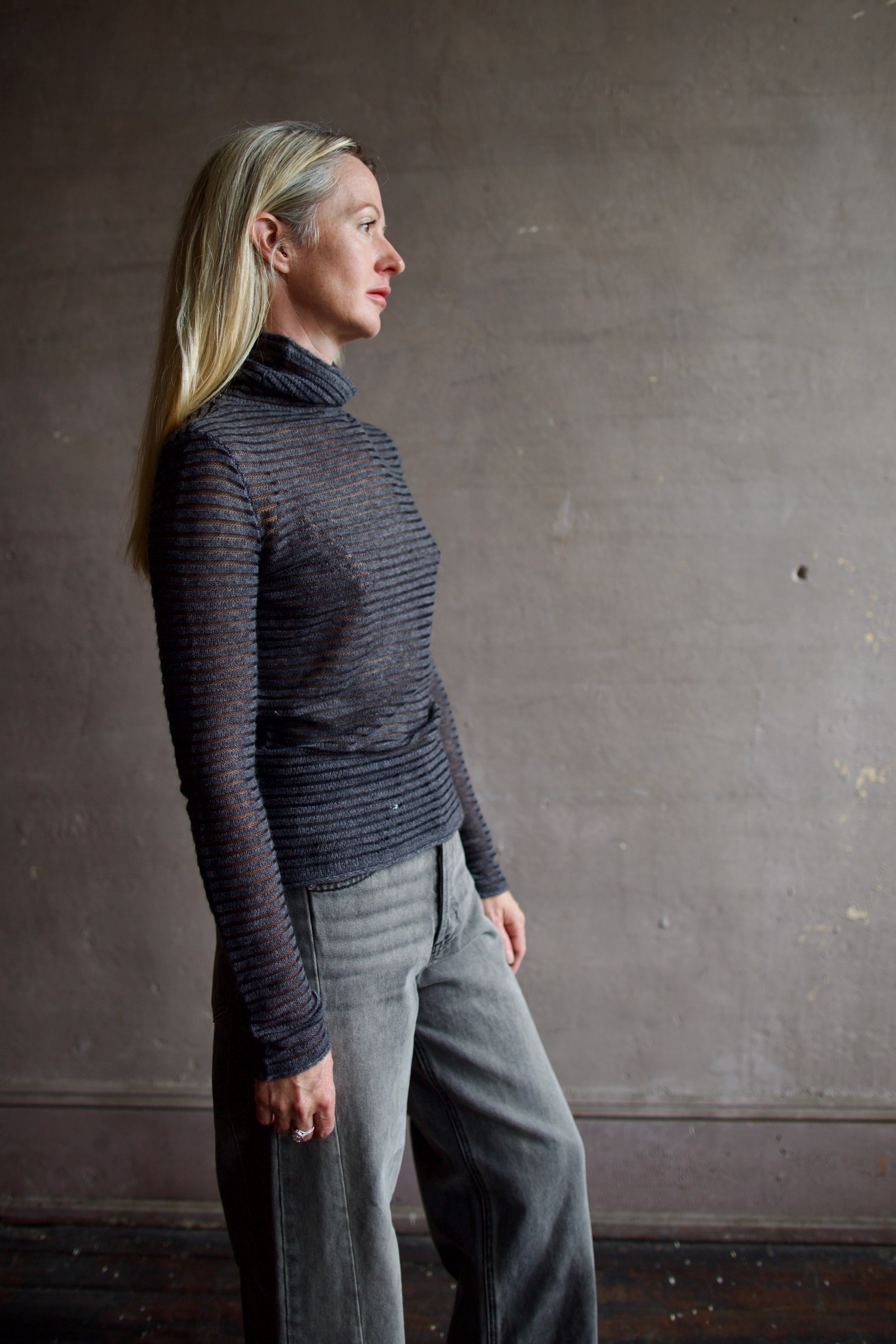 Model wearing a dark ribbed Proenza Schouler striped mock neck sweater and gray Veronica Beard barrel denim
