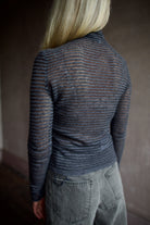 Model wearing a dark ribbed Proenza Schouler striped mock neck sweater and gray Veronica Beard barrel denim