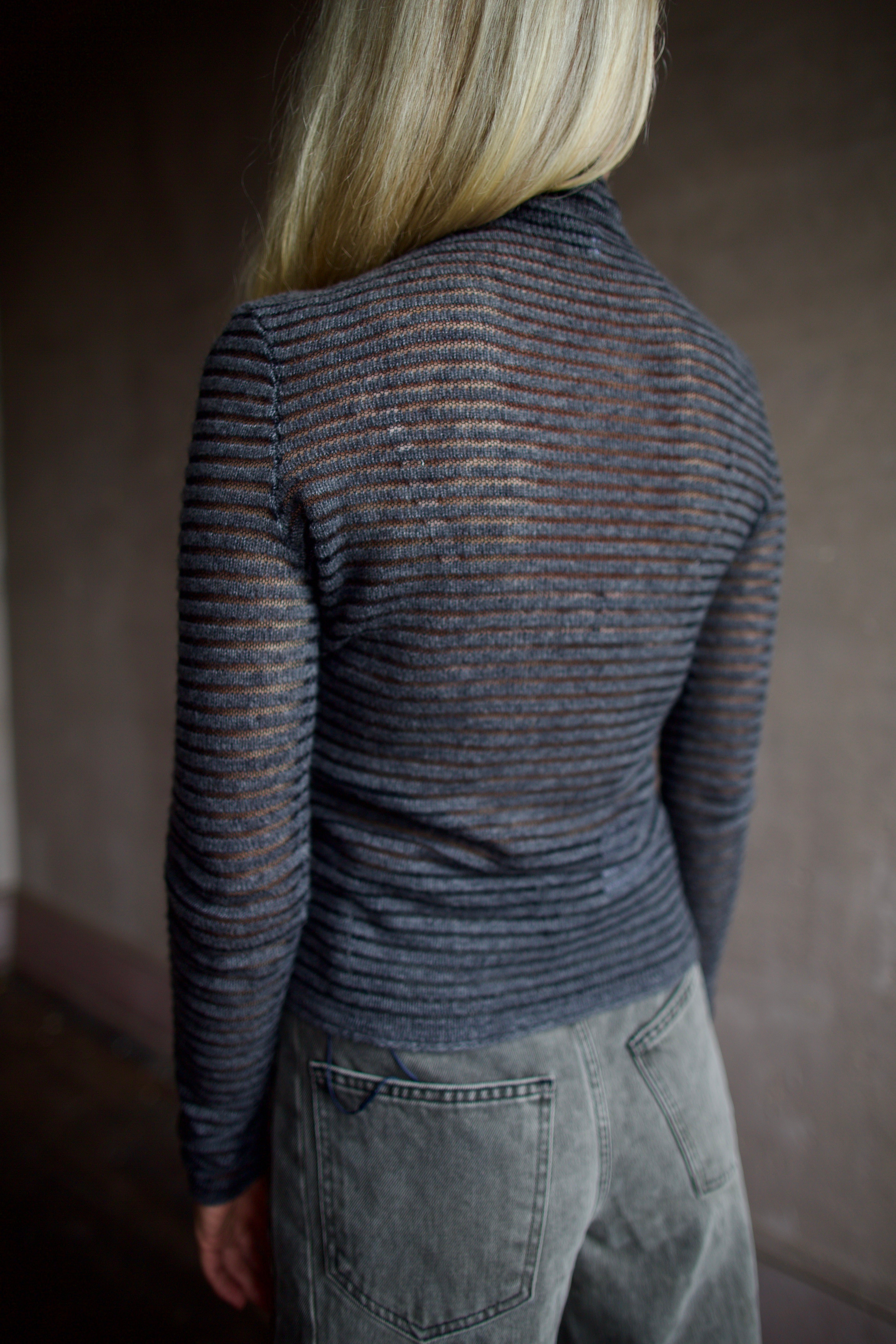 Model wearing a dark ribbed Proenza Schouler striped mock neck sweater and gray Veronica Beard barrel denim