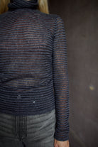 Model wearing a dark ribbed Proenza Schouler striped mock neck sweater and gray Veronica Beard barrel denim