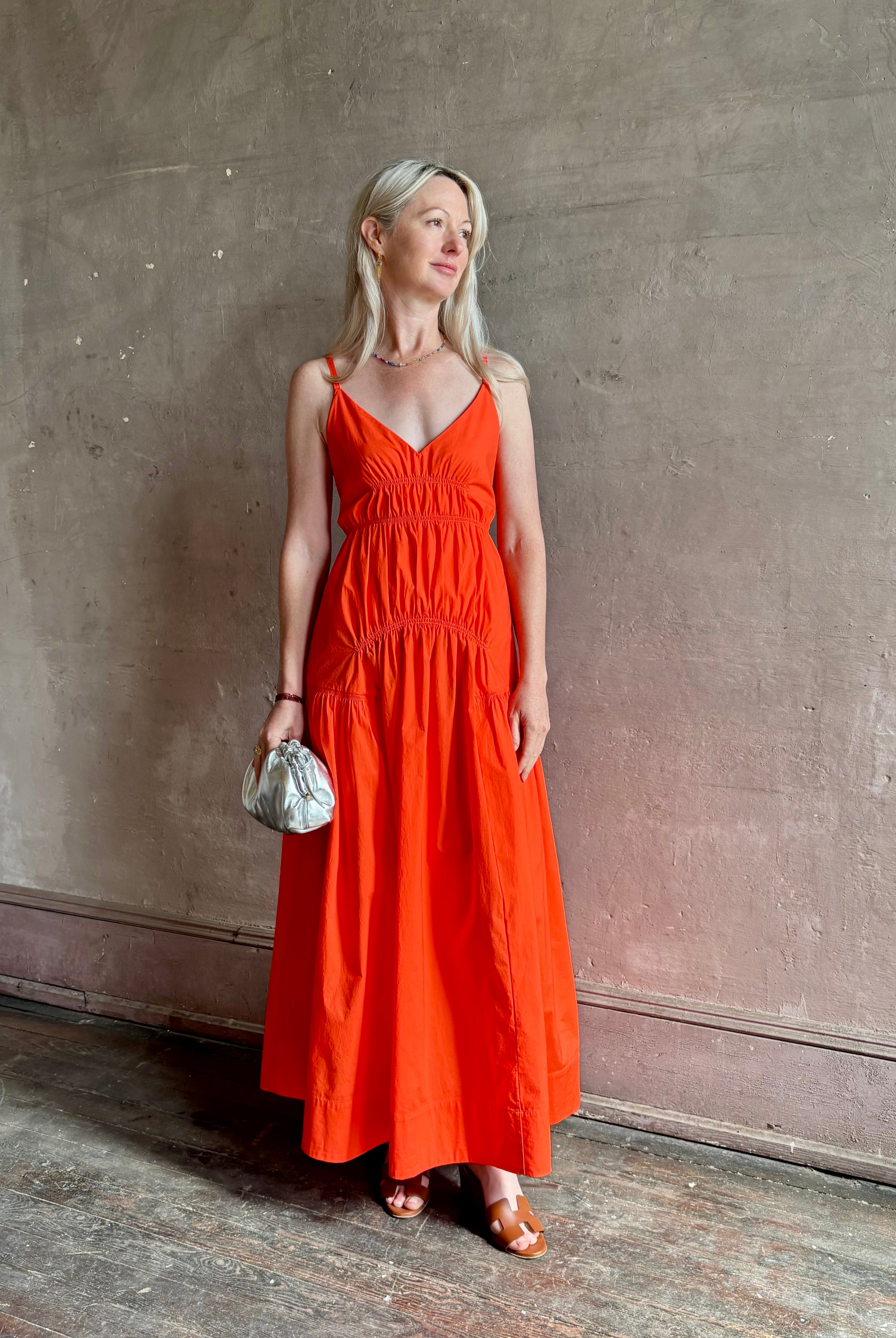 Mature woman wearing Michelyn maxi designer Dress from Proenza Schouler rendered in a striking orange and crafted from a refined cotton blend with adjustable spaghetti straps, v-neck, pockets, hidden zipper closure and modern ruching details