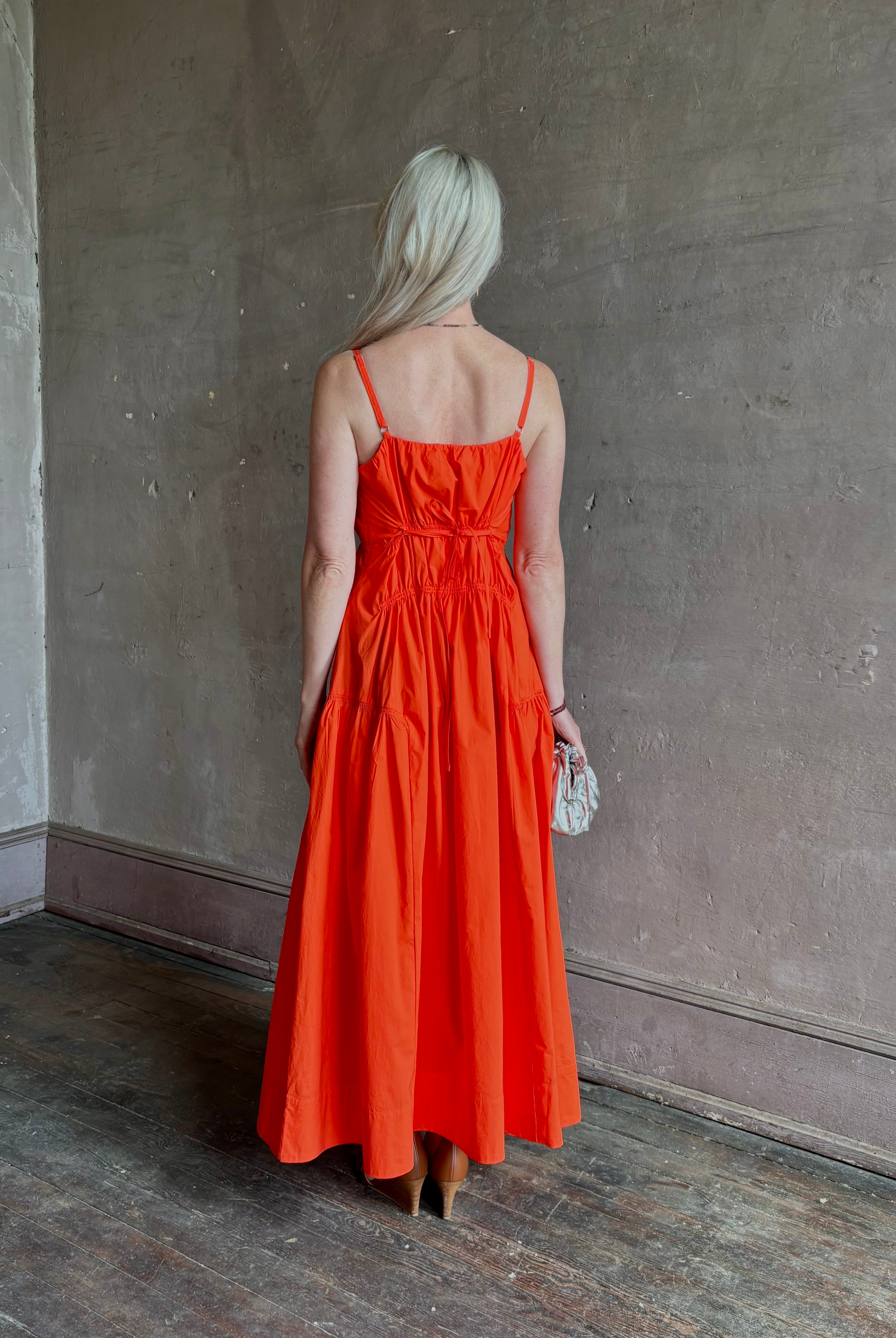 Mature woman wearing Michelyn maxi designer Dress from Proenza Schouler rendered in a striking orange and crafted from a refined cotton blend with adjustable spaghetti straps, v-neck, pockets, hidden zipper closure and modern ruching details
