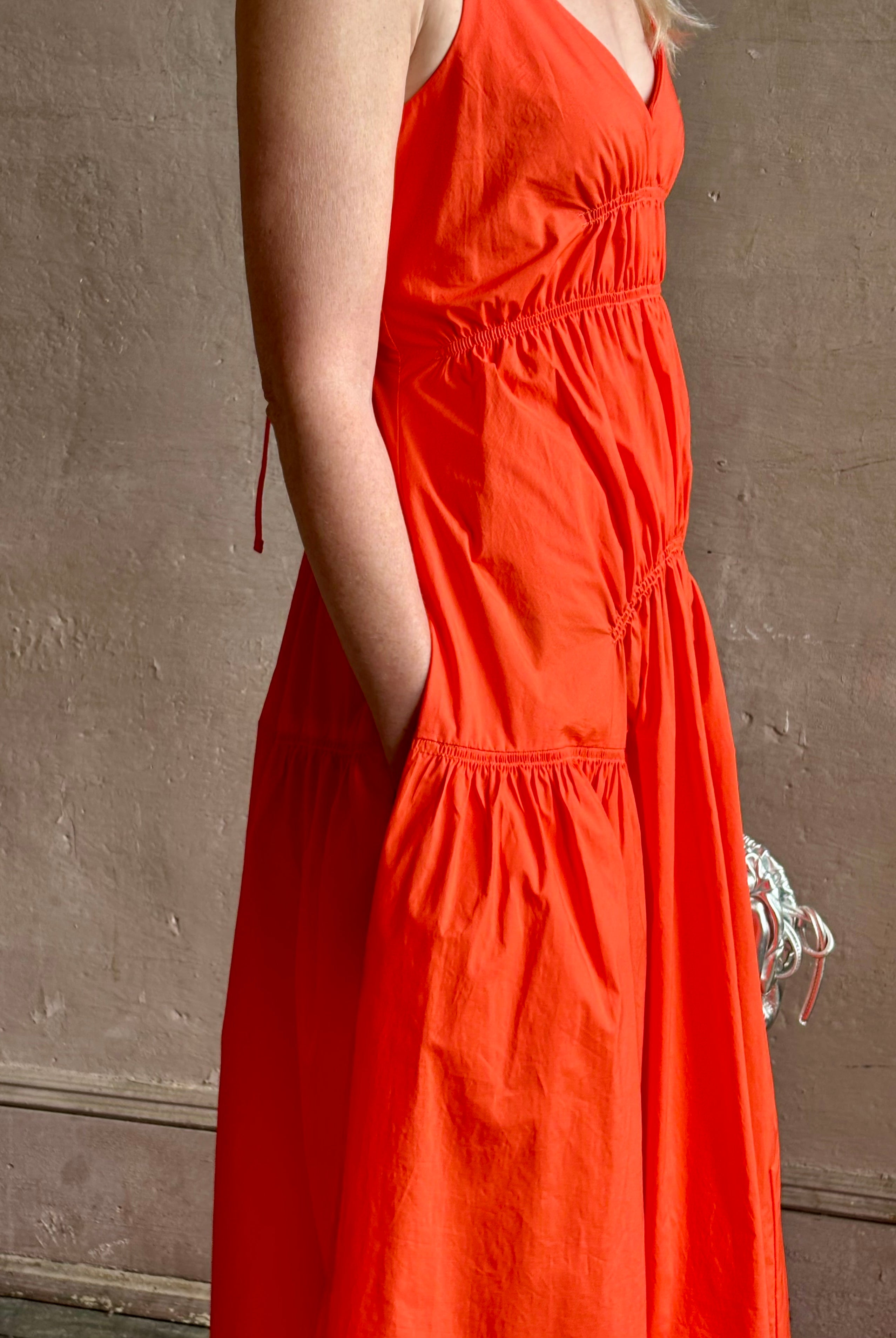 Mature woman wearing Michelyn maxi designer Dress from Proenza Schouler rendered in a striking orange and crafted from a refined cotton blend with adjustable spaghetti straps, v-neck, pockets, hidden zipper closure and modern ruching details