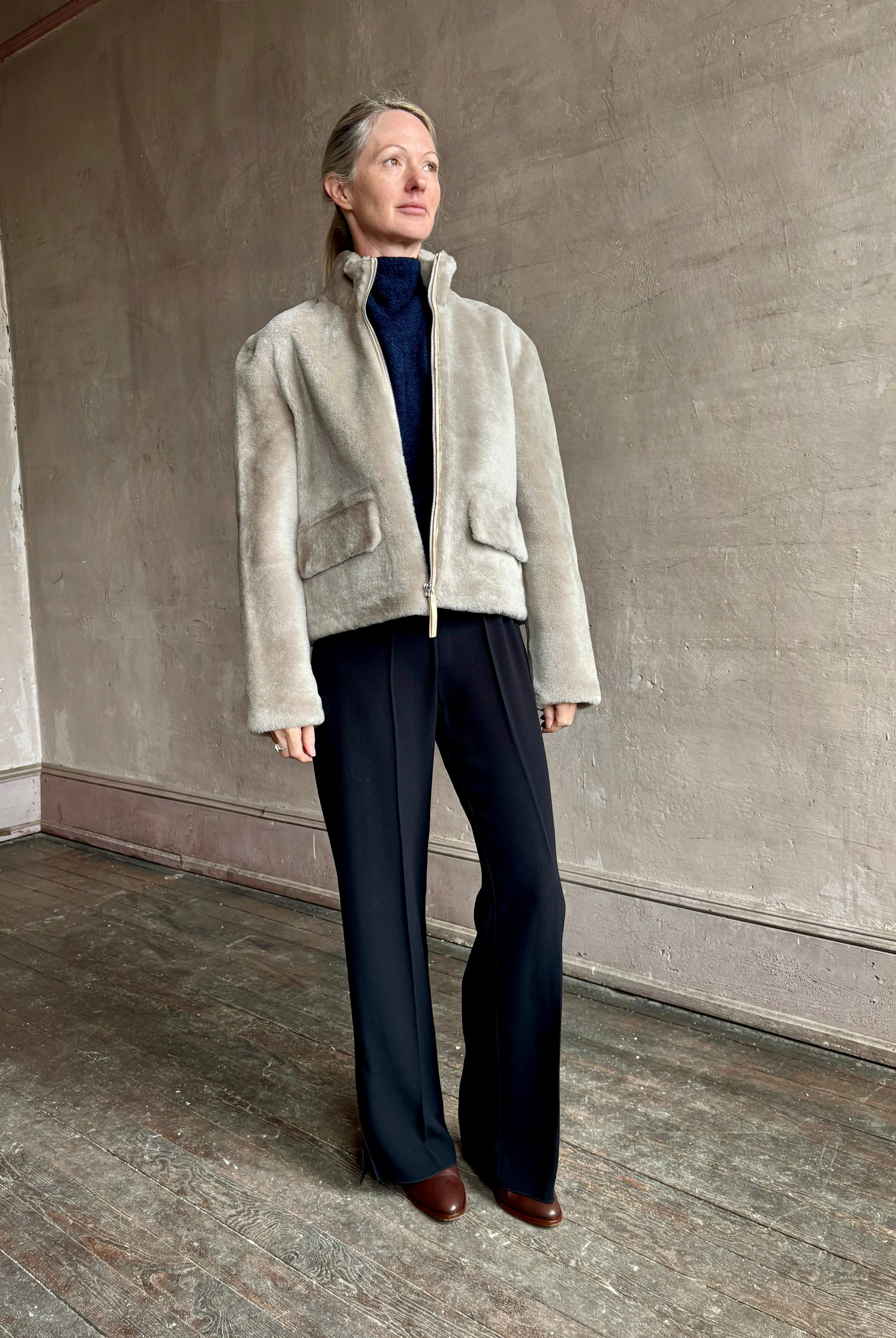 Image of a mature woman wearing Proenza Schouler Scarlett shearling jacket with a zip front and pockets for  the ultimate warm luxury coat in a neutral