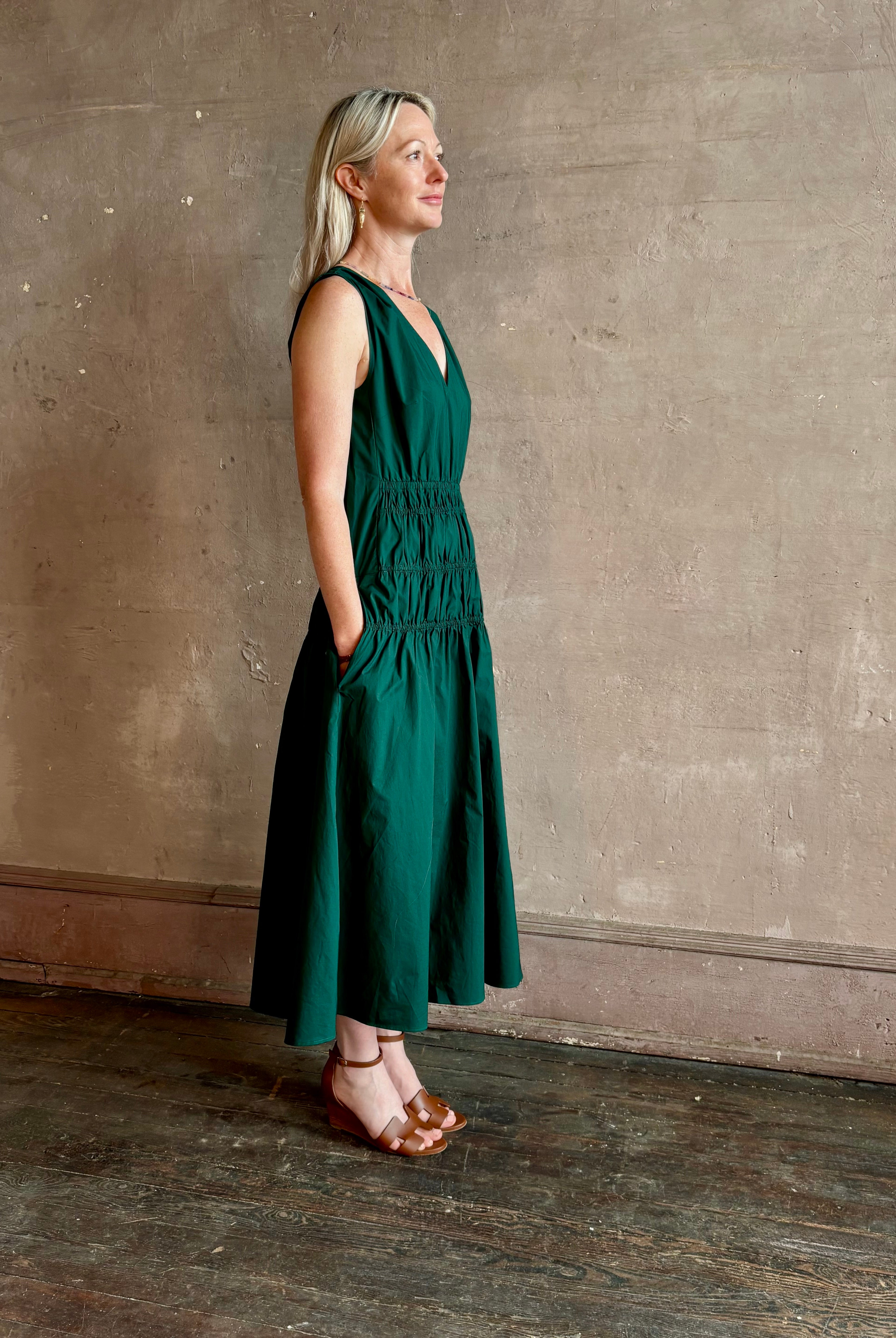 Mature woman wearing Loren Dress from Proenza Schouler White Lable rendered in aspruce green and crafted from a cotton elastane blend with v-neck, sleeveless, pockets, and rushed waist