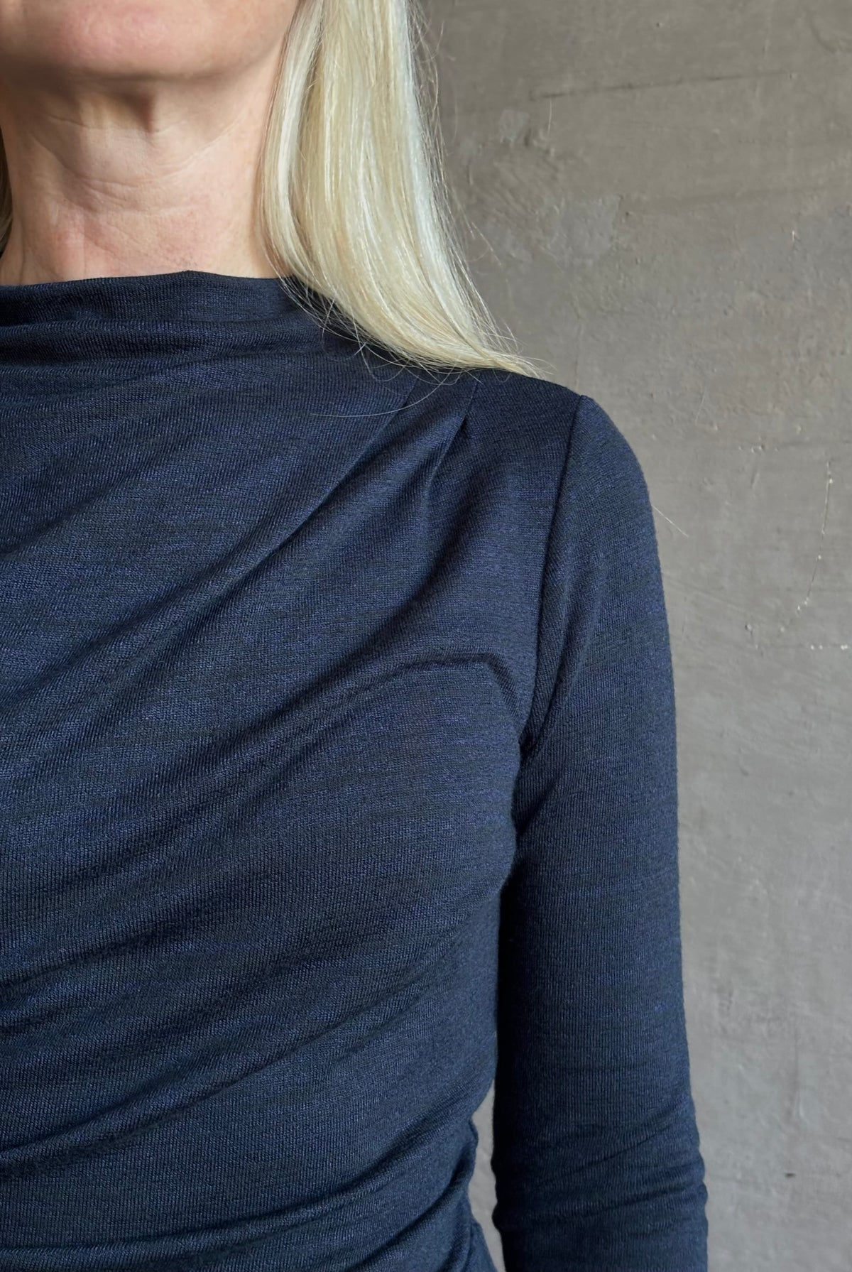 Close-up of a mature woman wearing Proenza Schoulder WL Mimi jersey top dark navy blue top showing the draped neckline and shoulder detail