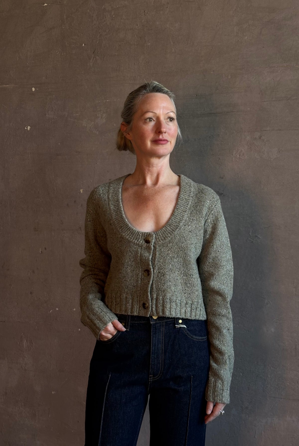 Mature woman wearing Rachel Comey Uridge Cardigan in Stone Green RWS-certified merino blend with U-neckline everyday layering