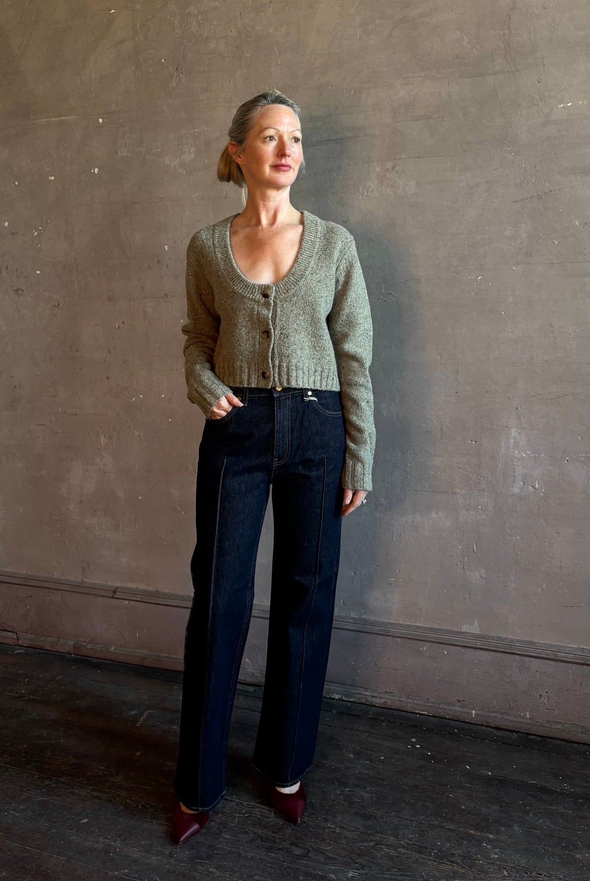 Mature woman wearing Rachel Comey Uridge Cardigan in Stone Green RWS-certified merino blend with U-neckline everyday layering