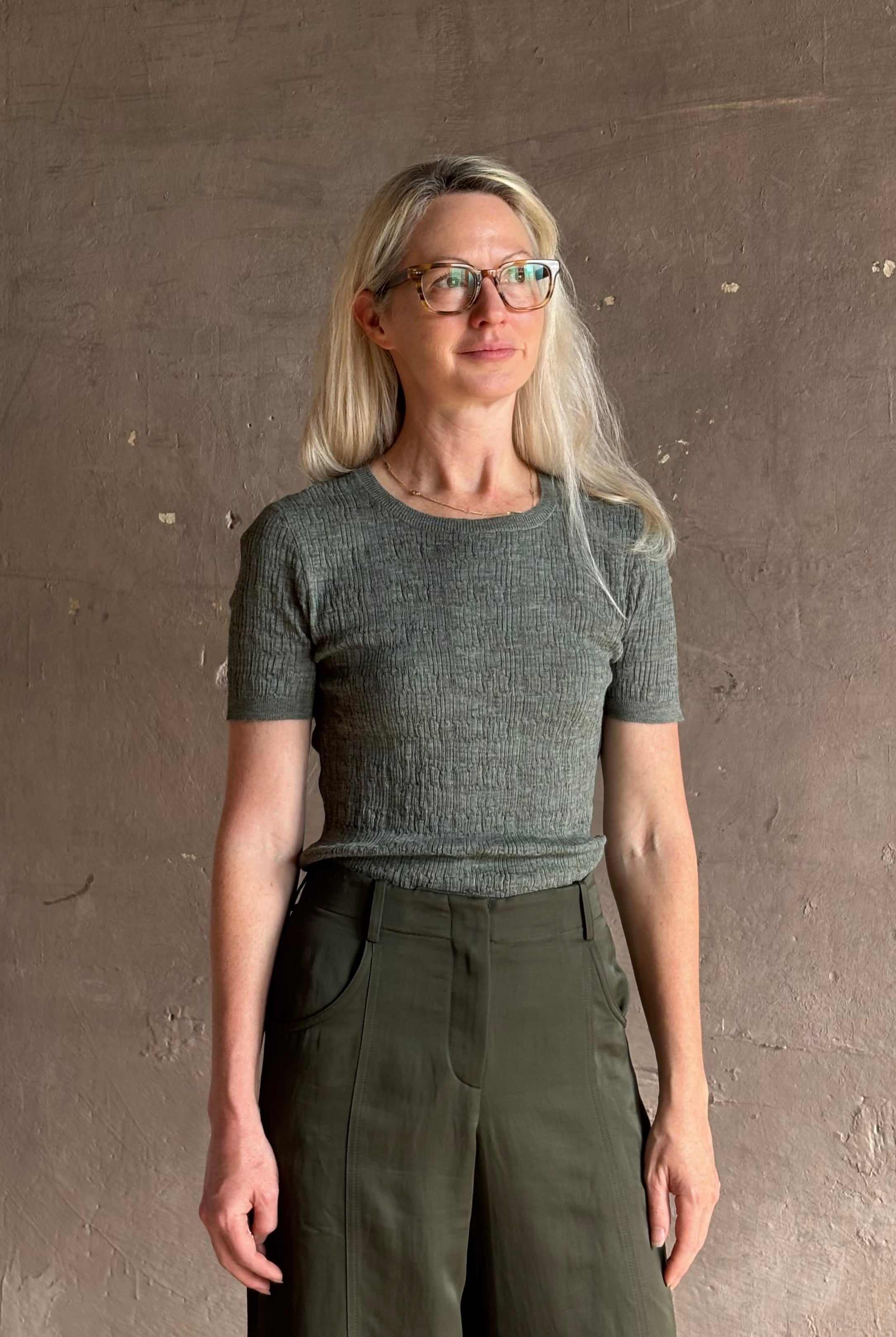 Mature woman wearing a textured short-sleeve fitted knit top in sage green round neckline with brown heathering