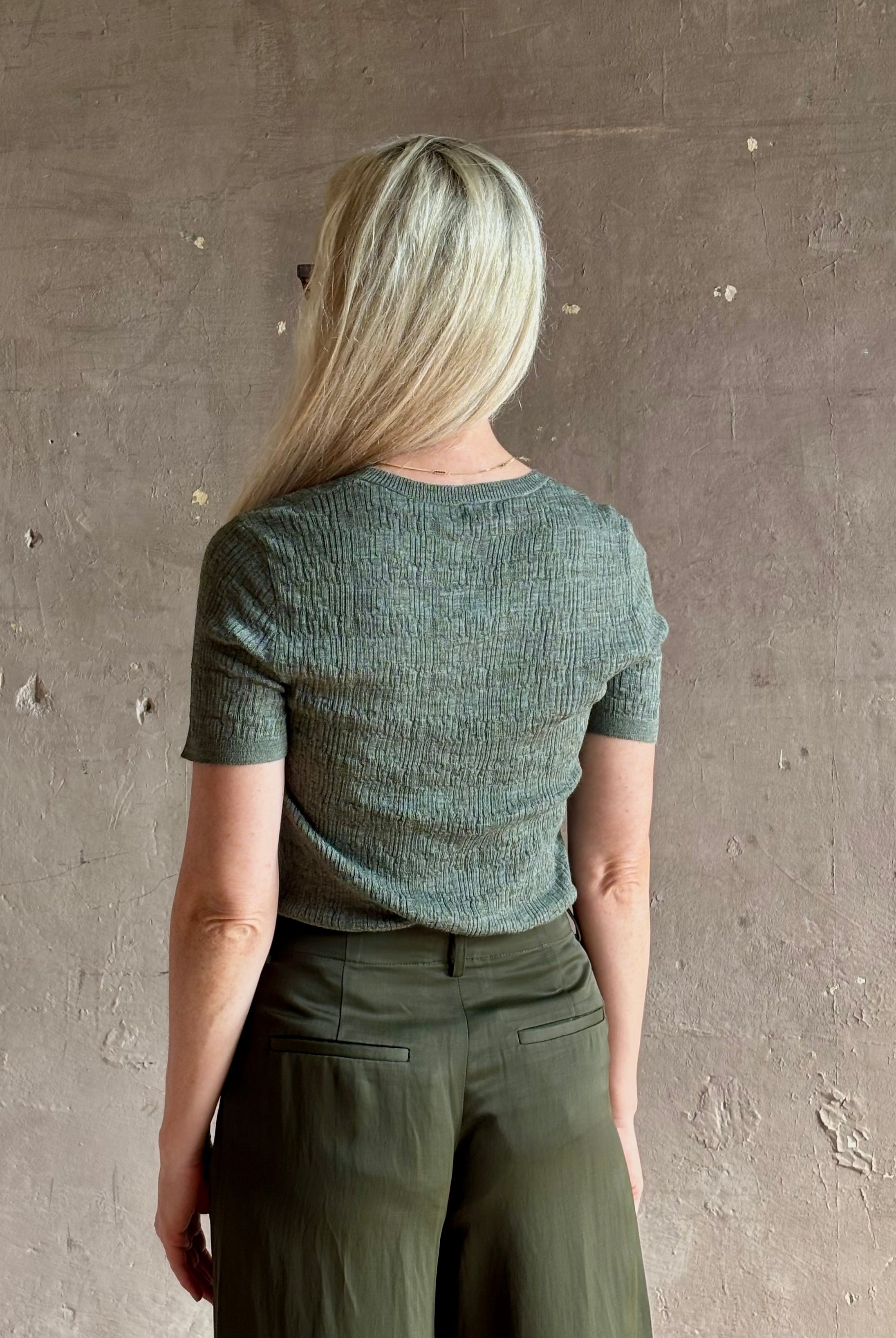 Mature woman wearing a textured short-sleeve fitted knit top in sage green round neckline with brown heathering