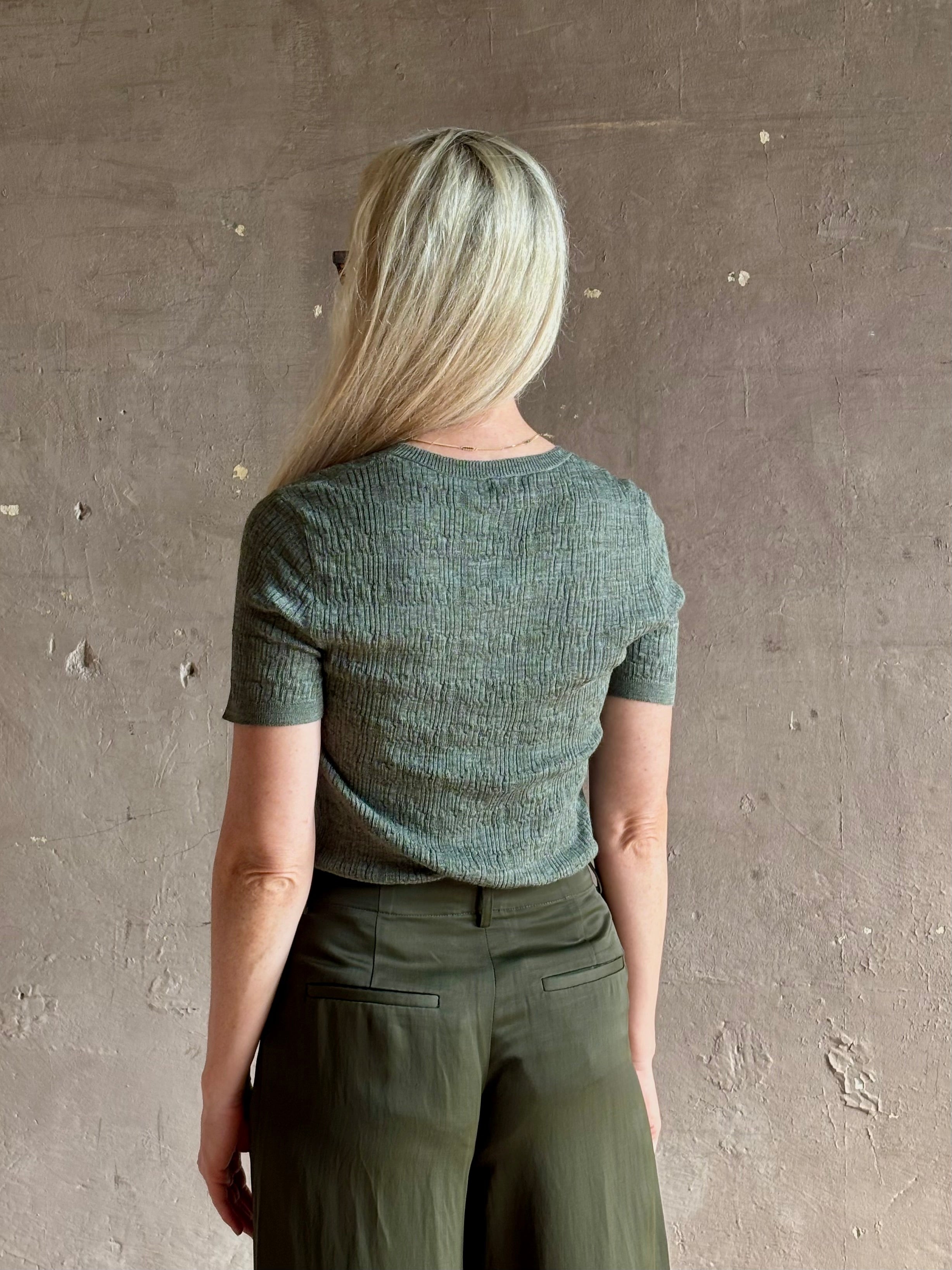 Mature woman wearing a textured short-sleeve fitted knit top in sage green round neckline with brown heathering