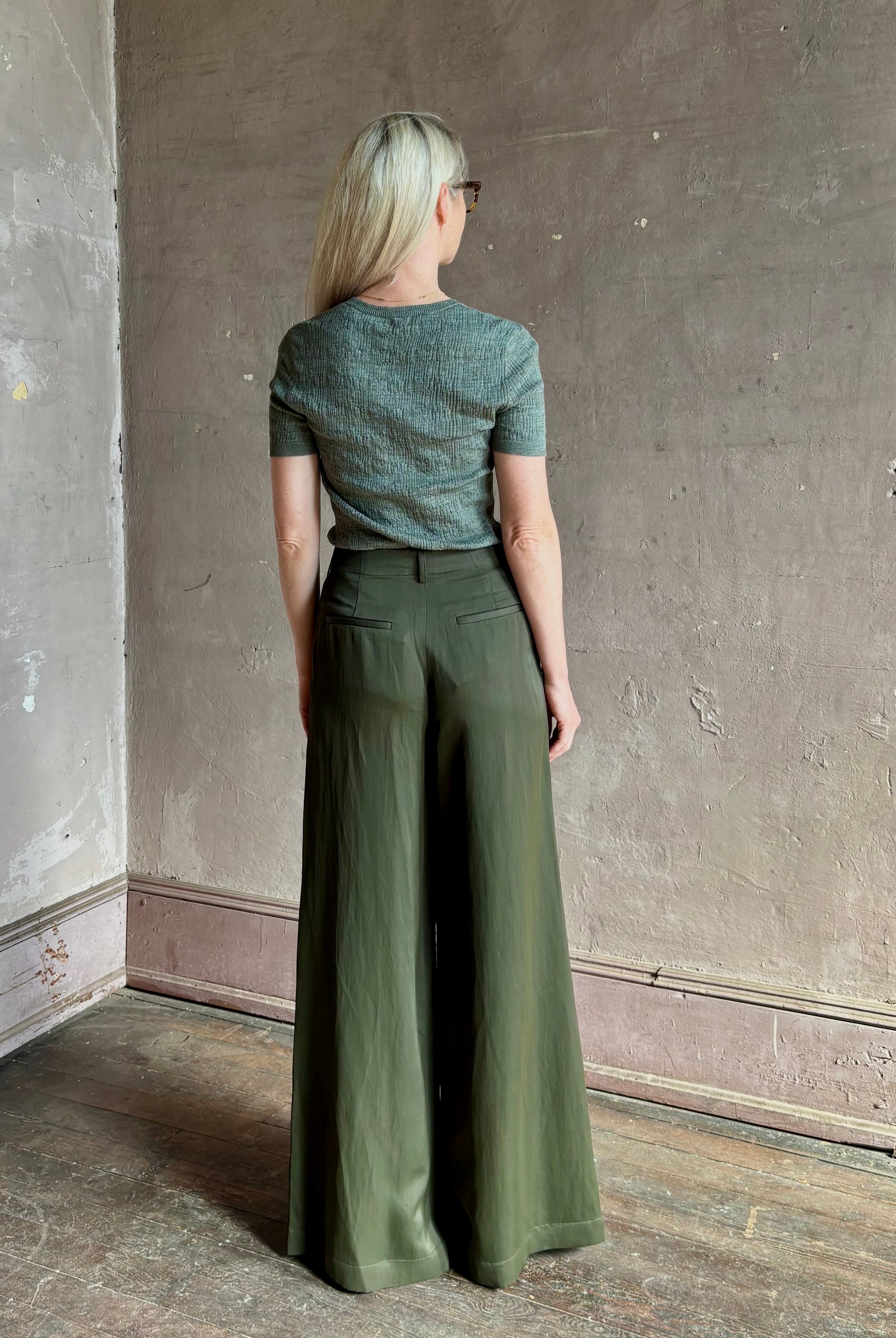Mature woman wearing a textured short-sleeve fitted knit top in sage green round neckline with brown heathering