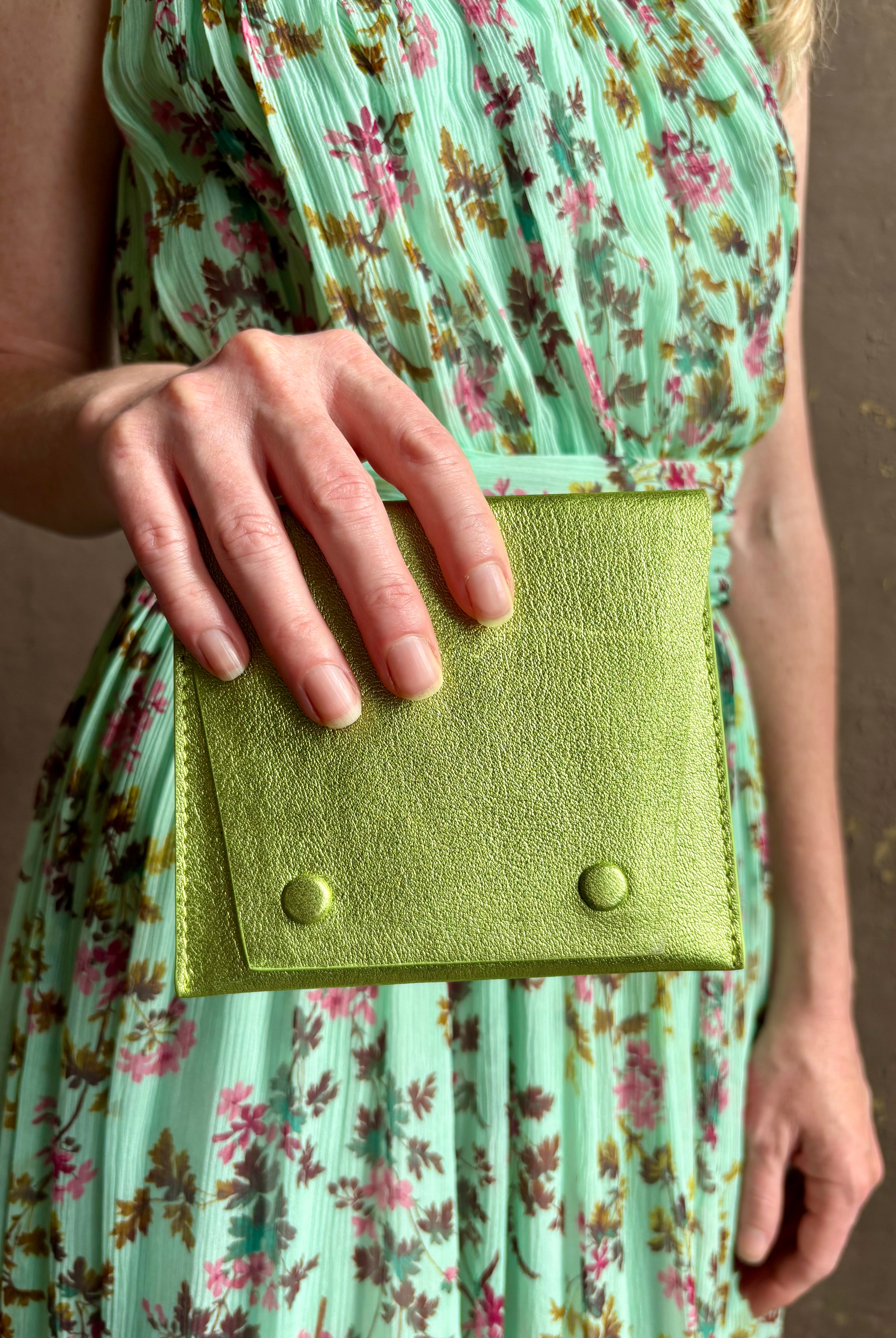 Woman holding Lime Wallet from Rachel Comey is a beautifully refined luxury accessory that is an everyday carry pieces. Crafted from 100% premium metallic leather to organize your purse