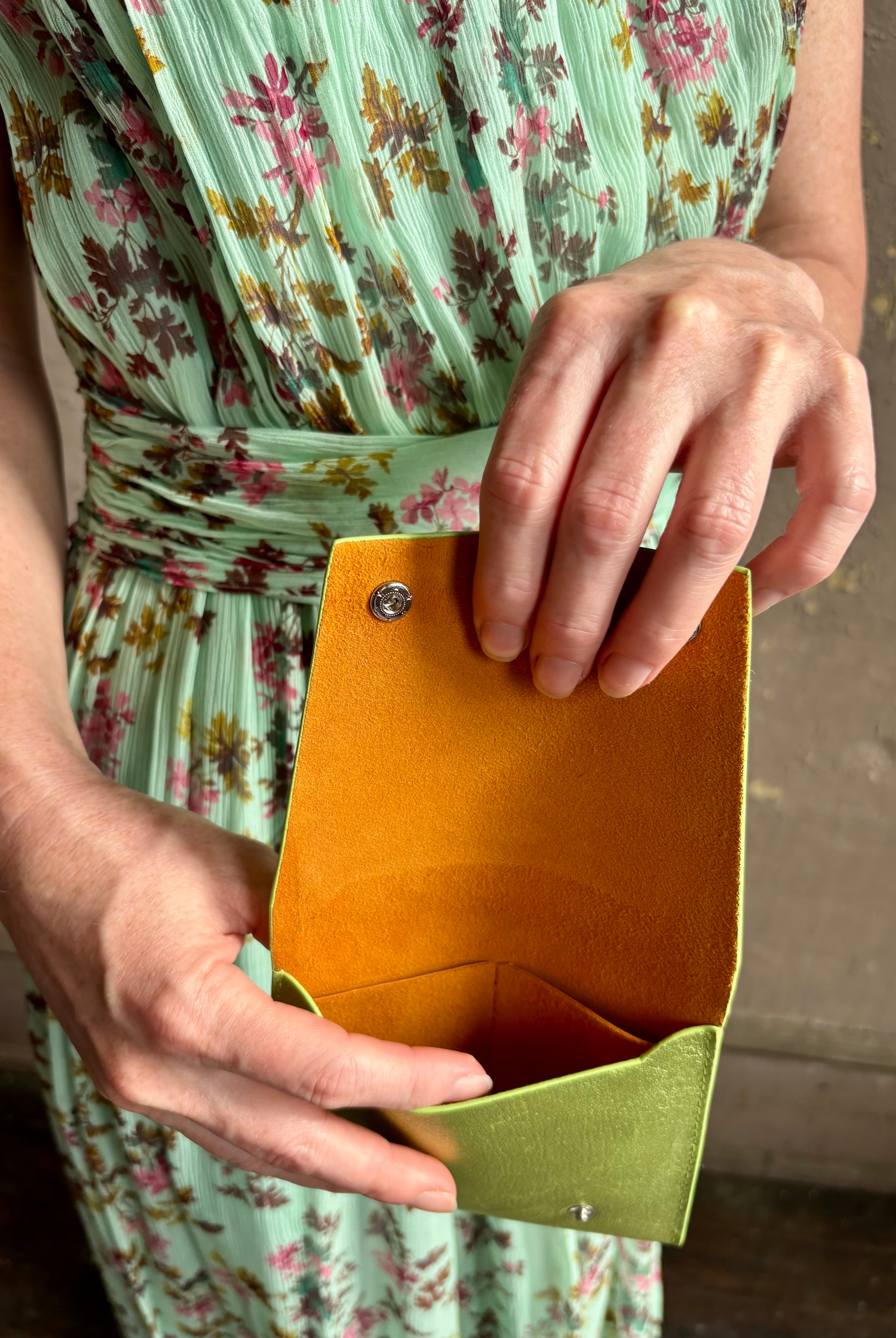 Woman holding Lime Wallet from Rachel Comey is a beautifully refined luxury accessory that is an everyday carry pieces. Crafted from 100% premium metallic leather to organize your purse with two snaps and interior pockets